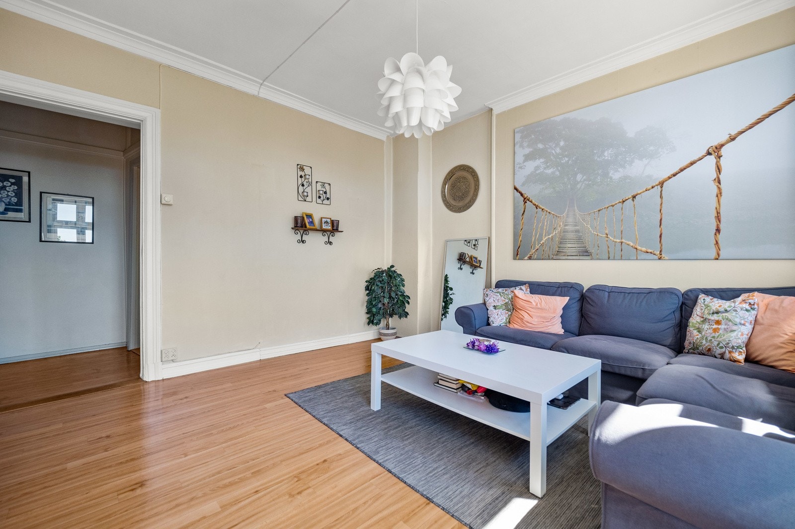 Stuen har stukkaturlignende listverk mot himlingen, lysbeige veggflater og parkettmønstret gulvbelegg. Galleribilde