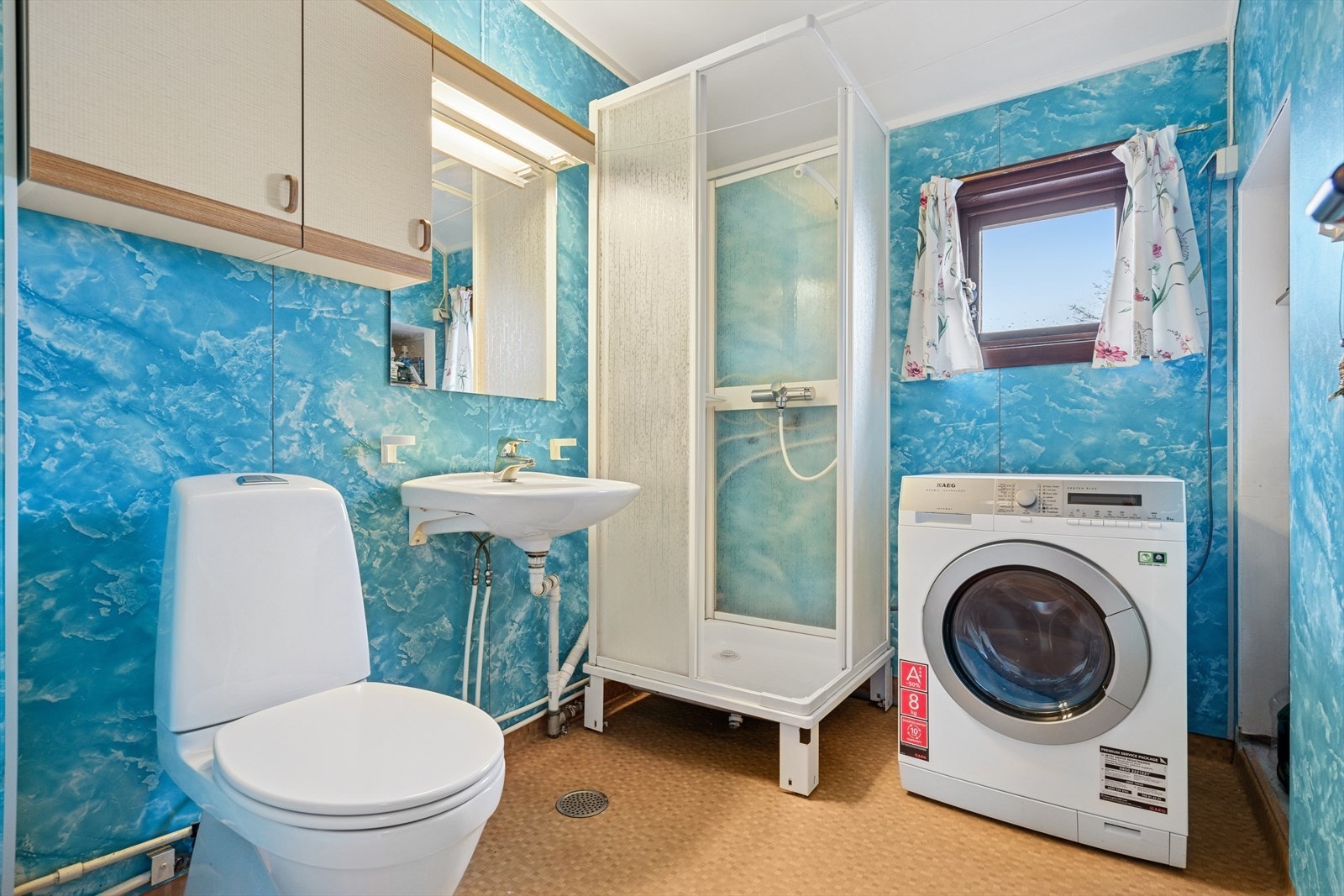 Eldre baderom med våtromsplater på vegg og vinyl på gulv. Opplegg for vaskemaskin. Galleribilde