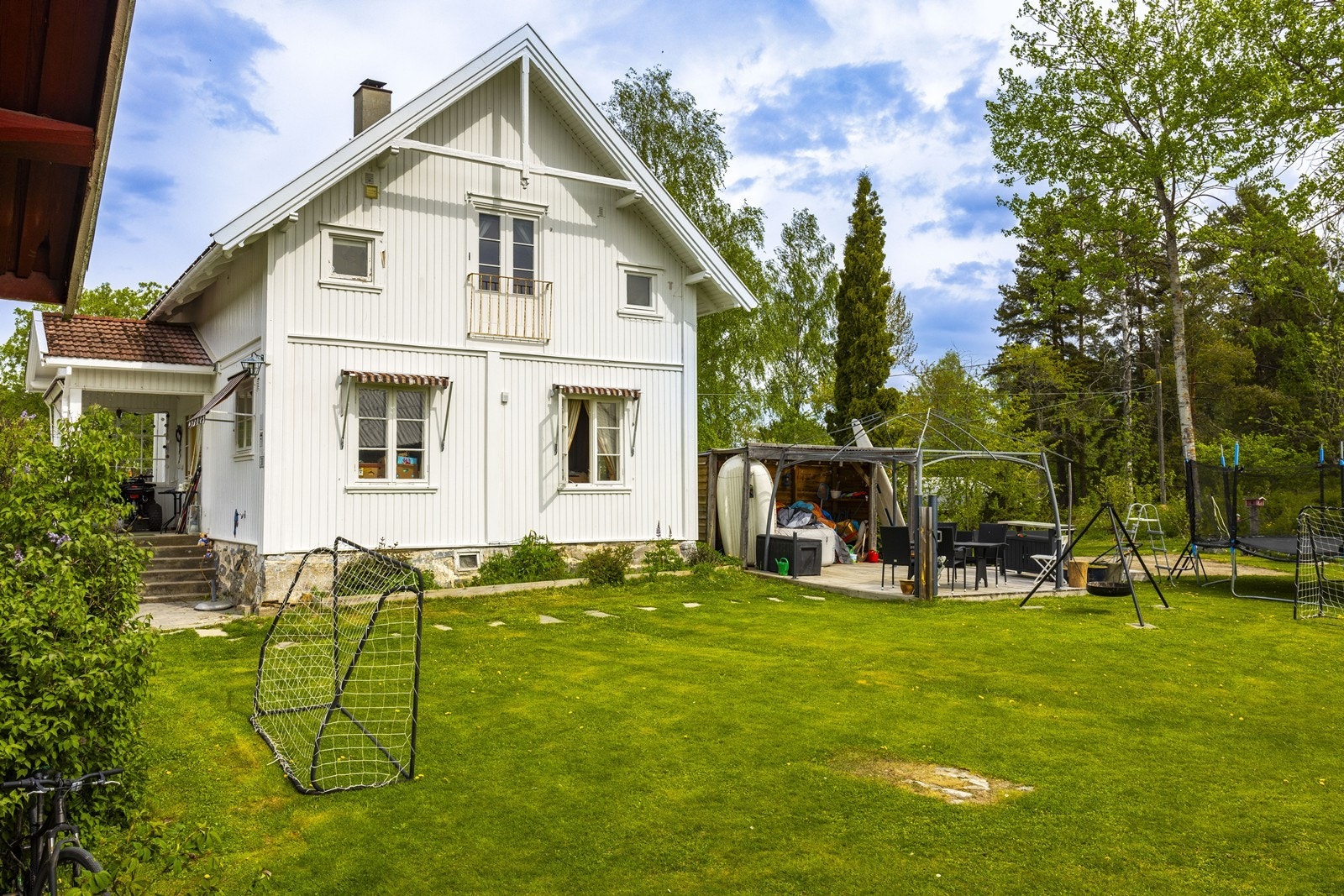 Gårdstunet er pent opparbeidet med plen mellom bygningene, hekk som skjermer, og en innbydende uteplass rett ved boligen. Galleribilde