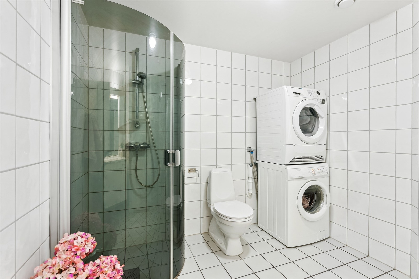 Badet er utstyrt med servant og underskap, dusjhjørne med dusjvegger i glass og gulvmontert toalett. Galleribilde