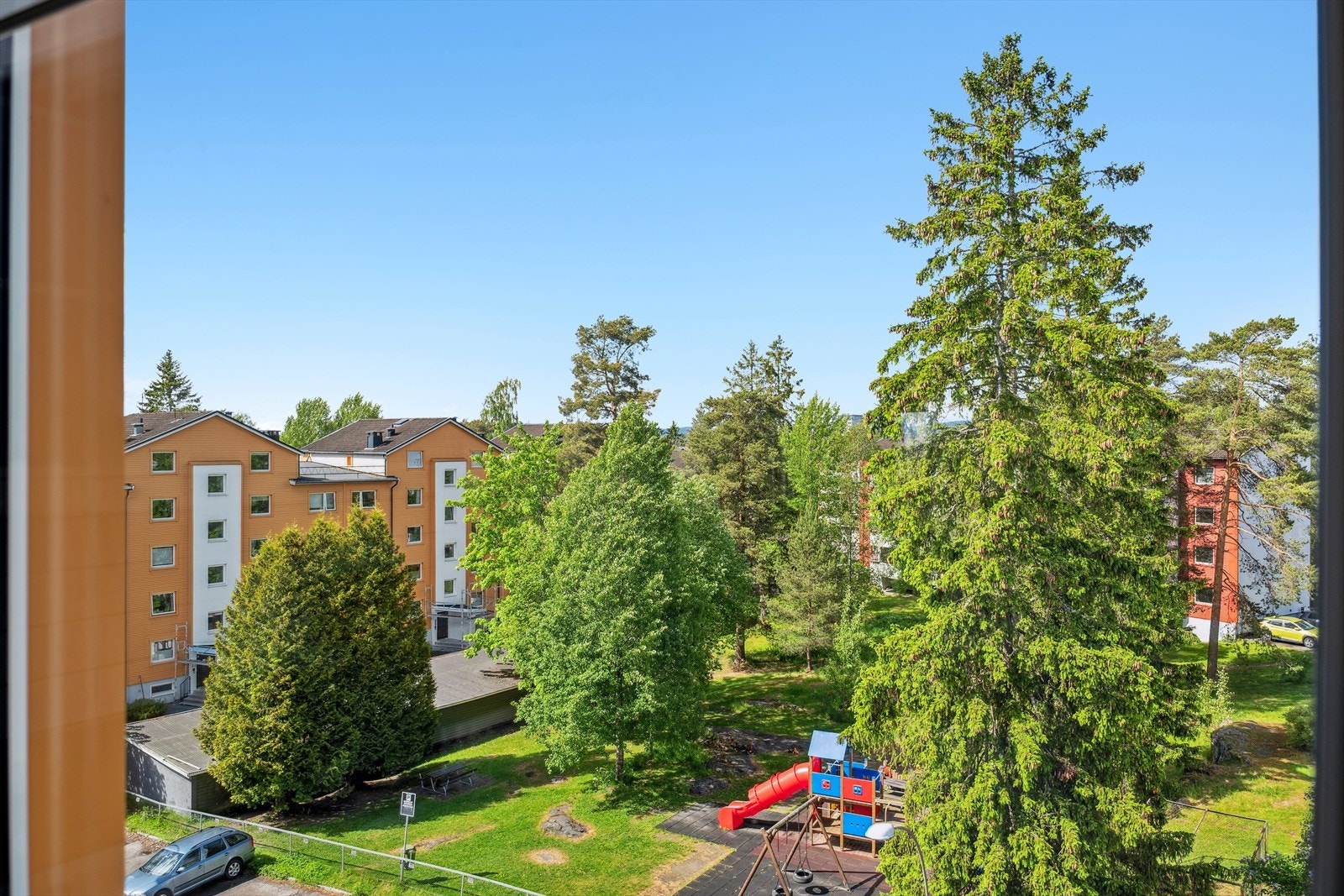 Tomten er pent opparbeidet med plen, diverse beplantning, trær, lekeplass, sittebenker og asfalterte arealer Galleribilde