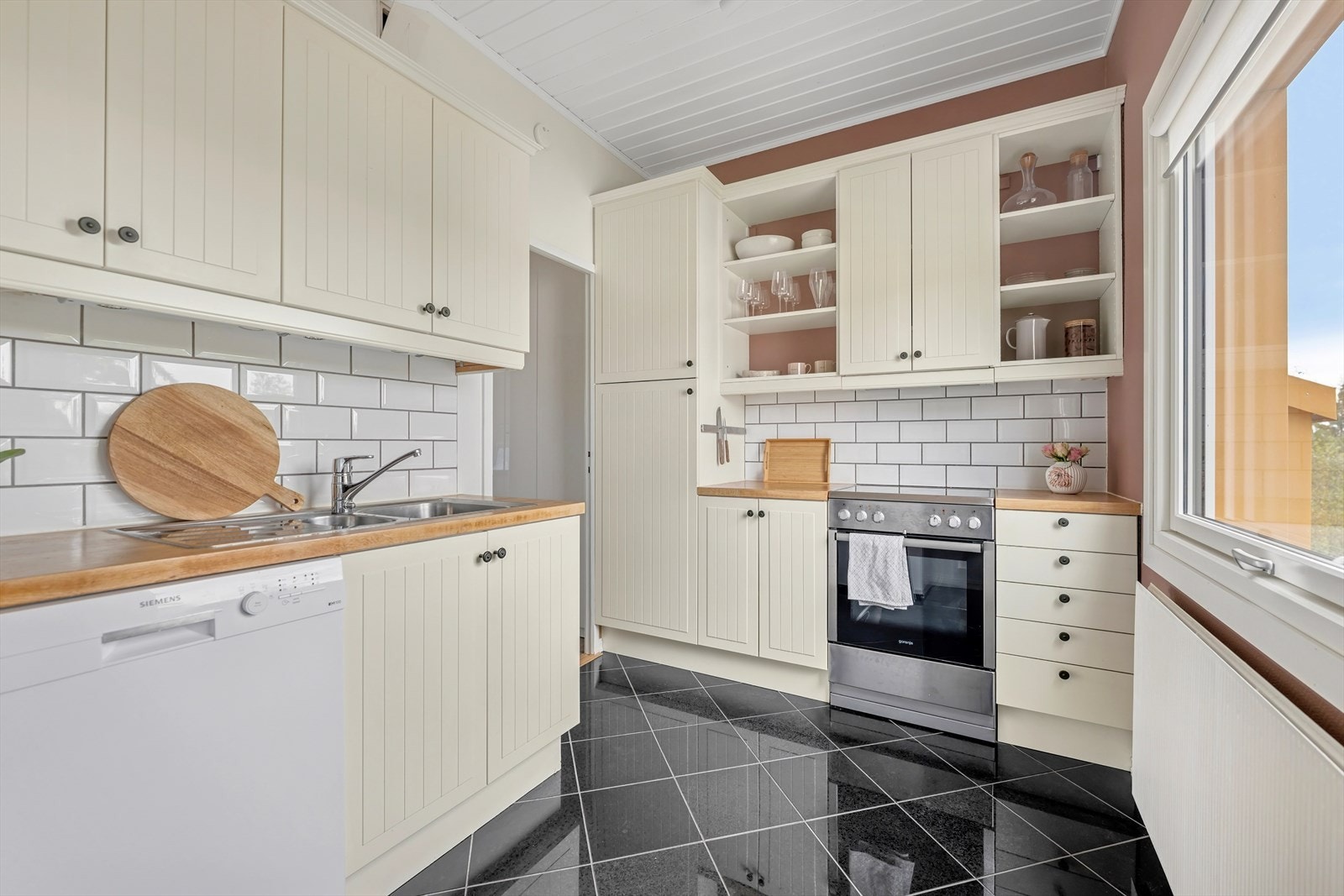 IKEA kjøkkeninnredning med lakkerte profilerte formpressede fronter, heltre eik benkeplate med fliser over, 1 ½ oppvaskkum med benkebeslag og kjøkkenventilator i stål Galleribilde