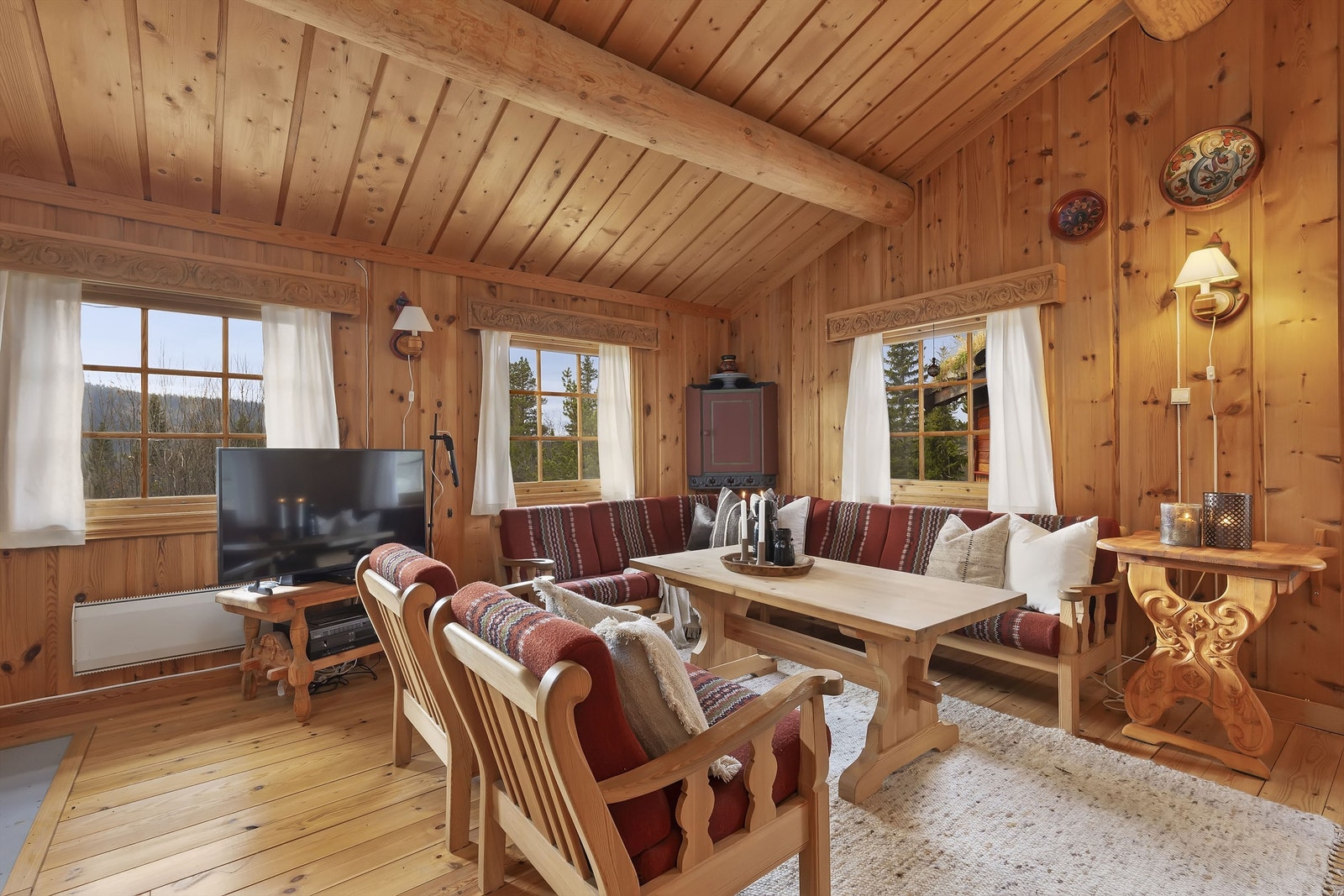 Stue med luftig skråtak og synlige rundstokker i taket Galleribilde