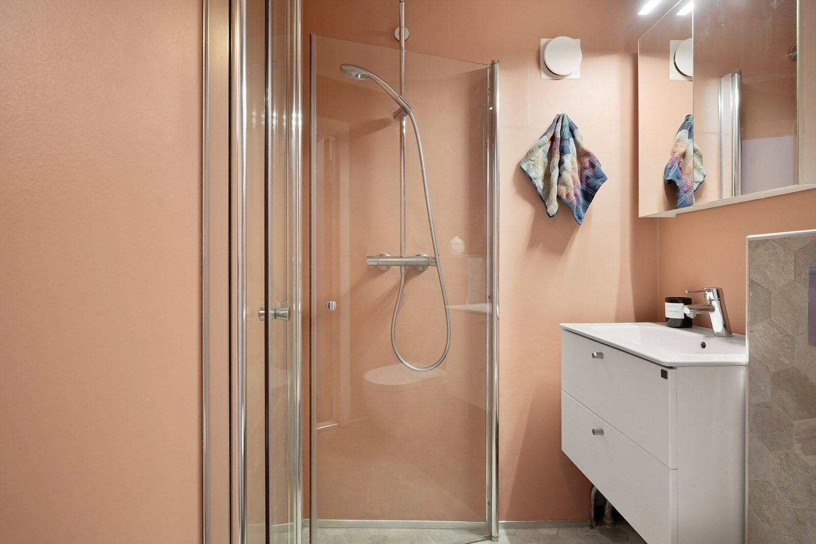 Servantskap fra Ballingslöv, med slette fronter og en matchende hvit keramisk servant med blandebatteri er fra Grohe i rustfritt stål. Over servanten er det et praktisk speilskap. Galleribilde