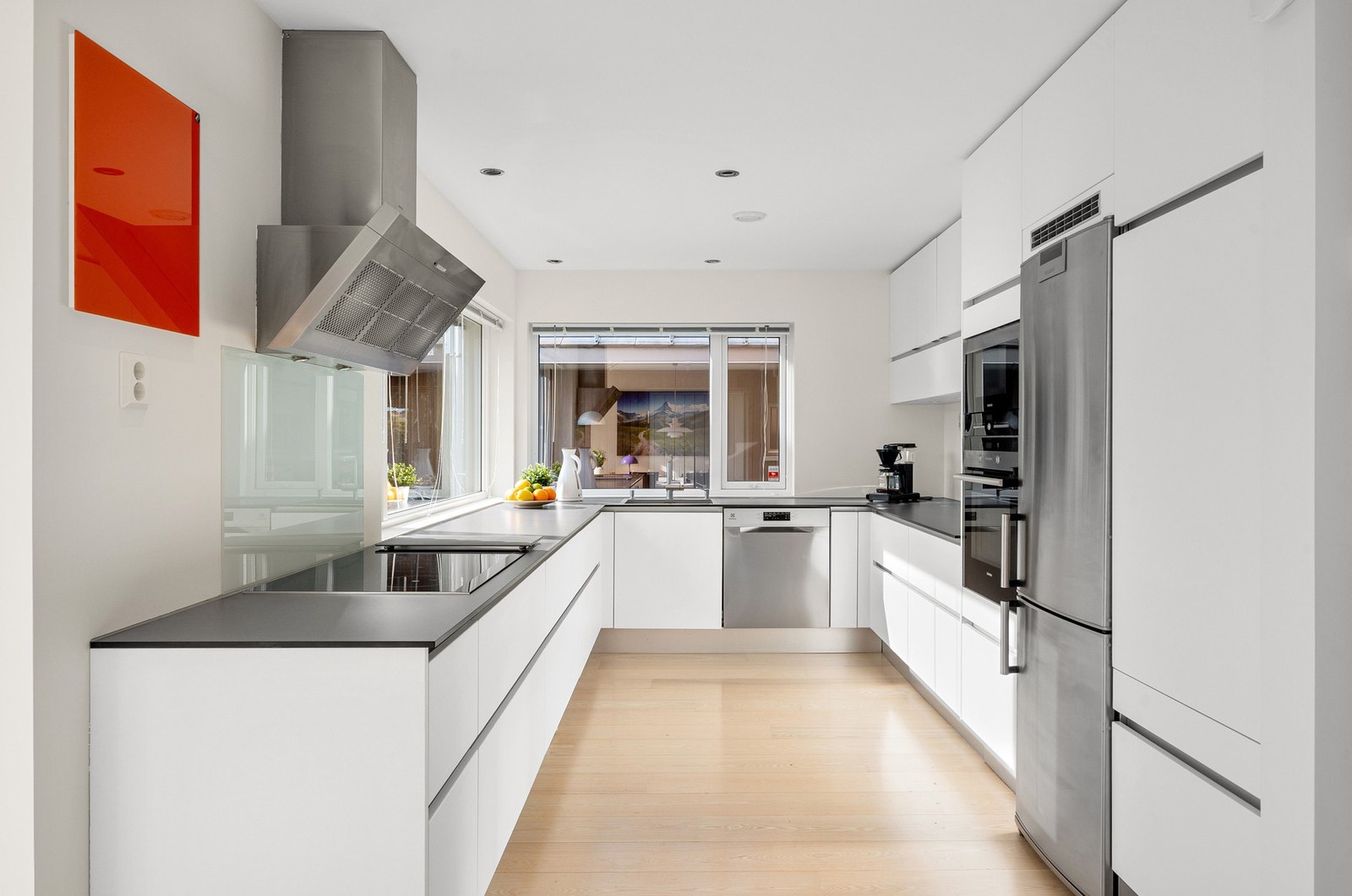 Kjøkkeninnredning med plane fronter og kompaktlaminat benkeplate. Kran og avløp for oppvaskmaskin. Integrert induksjonsplatetopp, stekeovn og mikrobølgeovn. Galleribilde