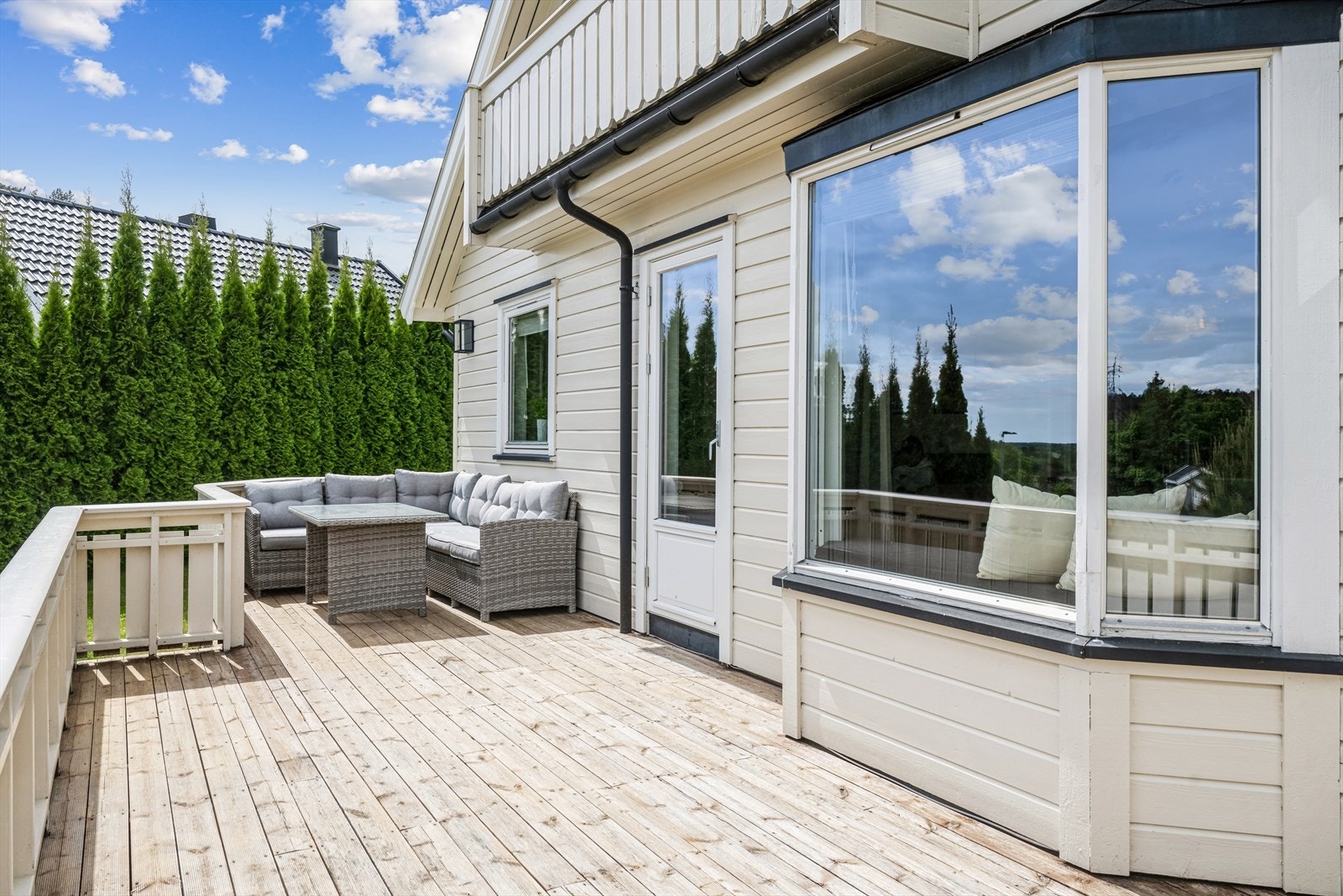 Stor solrik terrasse med gløtt av sjøen med formiddagssol Galleribilde