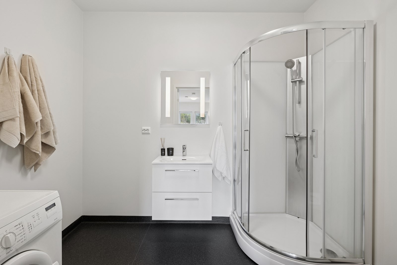 Badet har våtromstapet på vegger og malt gips i himling. Innredet med toalett, dusjkabinett, og baderomsinnredning. Opplegg for vaskemaskin. Galleribilde