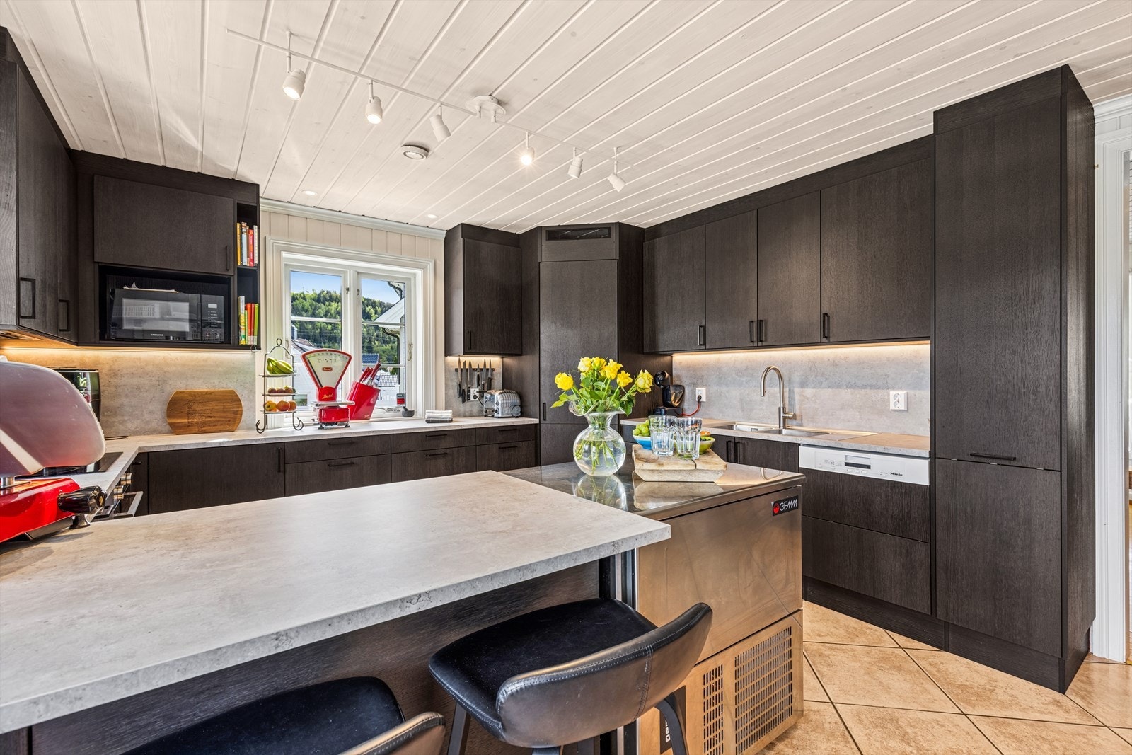 Integrerte hvitevarer som komfyr, platetopp, oppvaskmaskin og kjølehjørne. På armaturet er det installert Quooker. Galleribilde