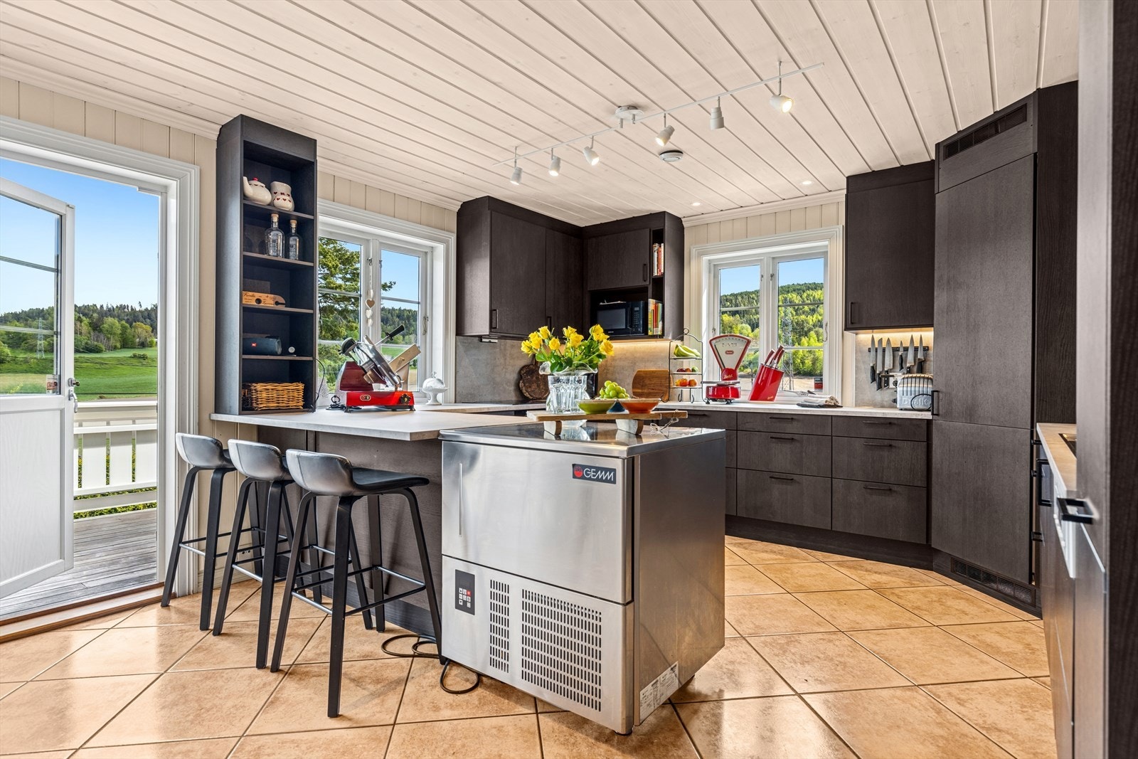 Et godt opplyst kjøkken som bader i lys fra store vindusflater. Ikke minst er det hyggelig å enkelt kunne ta med seg måltidene og nyte dem på terrassen rett utenfor. Galleribilde