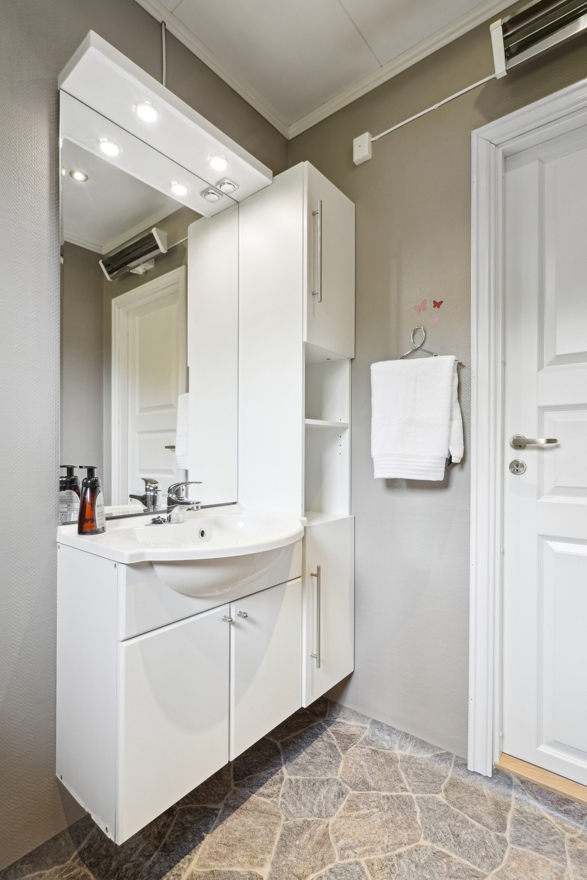 Baderommet er opparbeidet med gulvbelegg på gulv med elektrisk oppvarming, vegger med tapet og malte himlingsplater i tak. Galleribilde