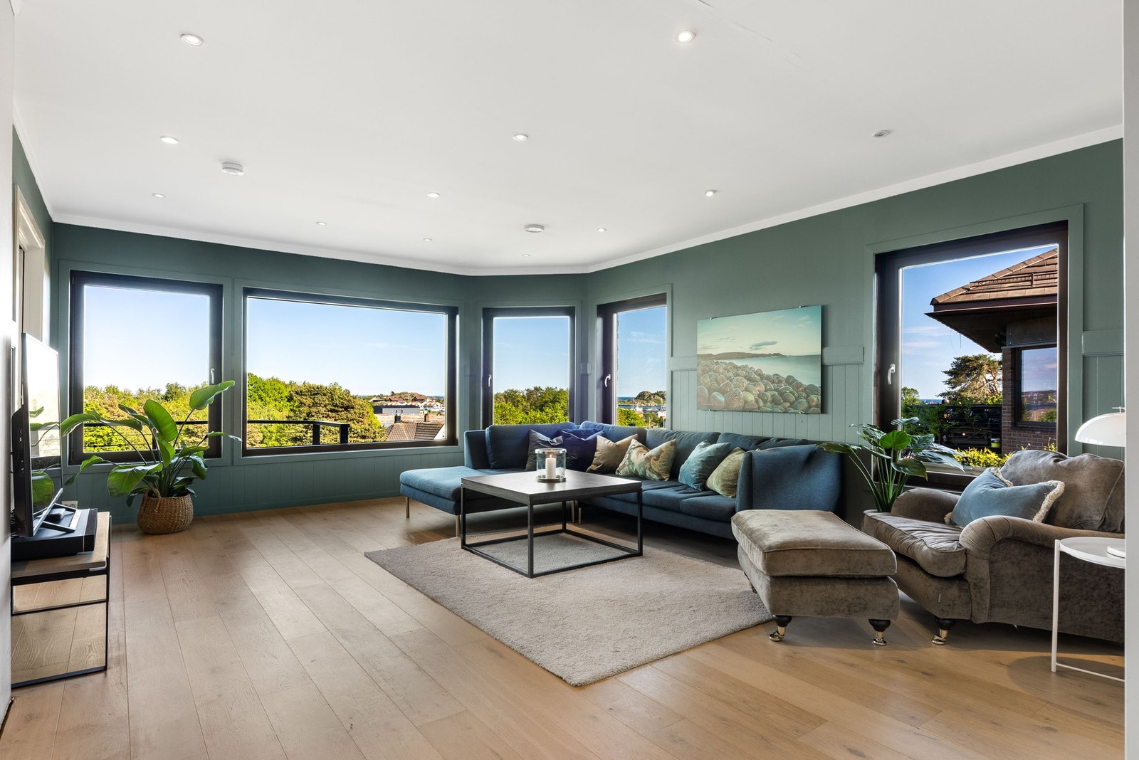 Stuen har store vinduer som slipper lys og naturen inn. Galleribilde