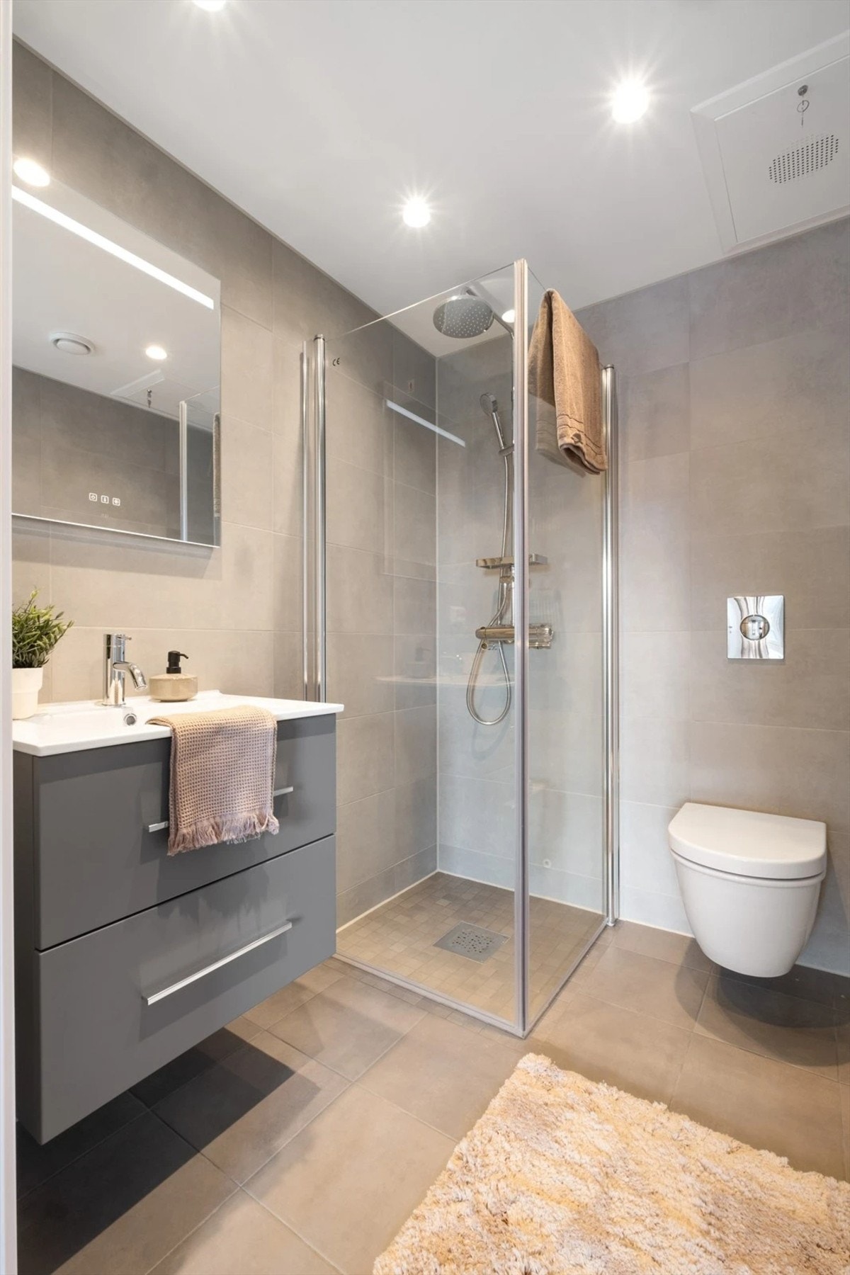 Innbydende flislagt baderom med gulvvarme og opplegg for vaskemaskin. Galleribilde