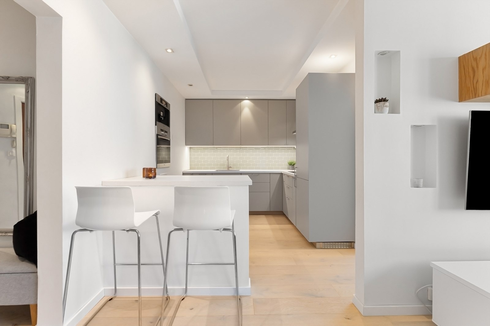 Stilrent IKEA-kjøkken fra 2025 med glatte fronter, laminat benkeplate og integrerte hvitevarer fra Miele. Galleribilde