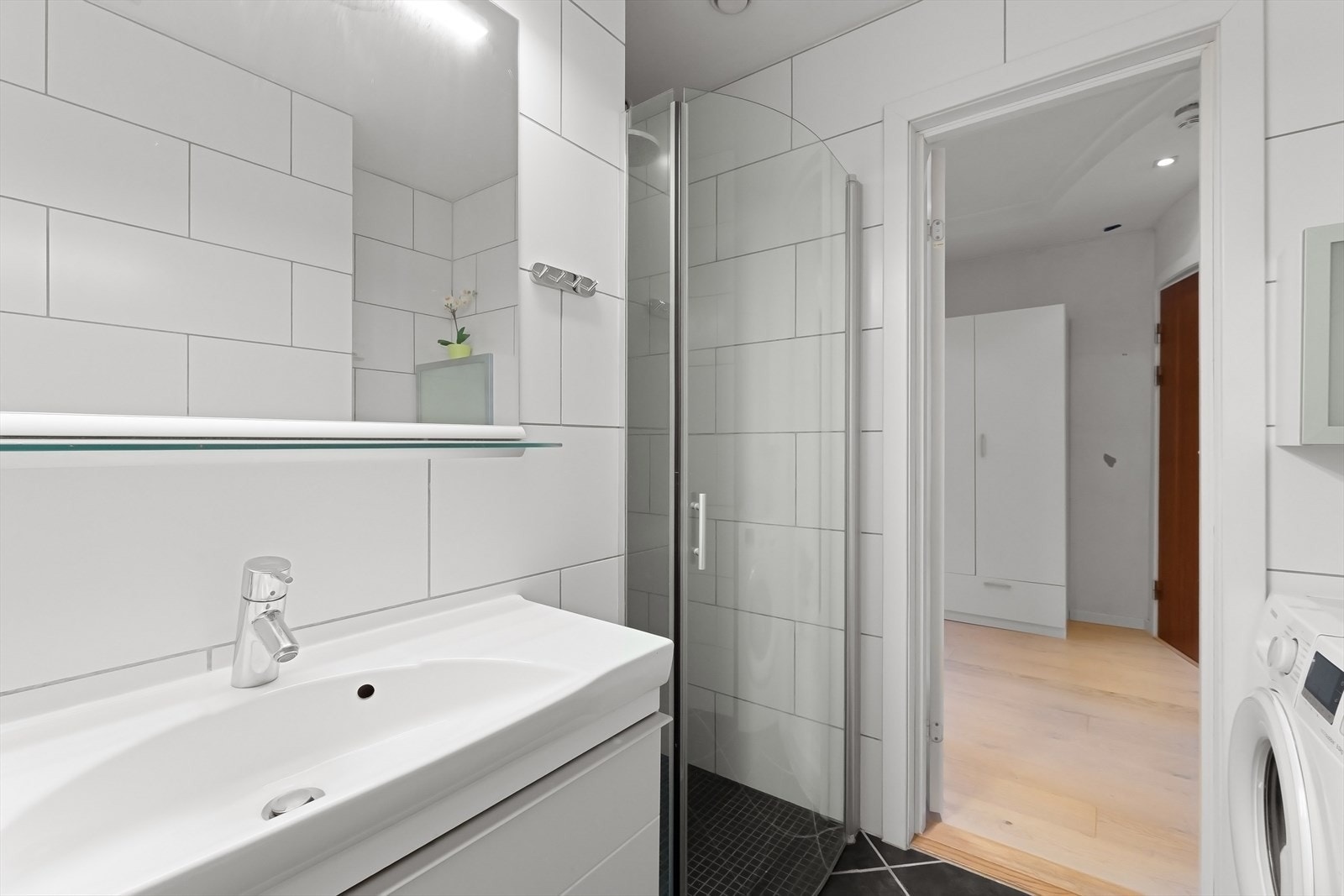 Badet består av flislagt gulv, flislagte vegger og malt himling. Badet er utstyrt med dusjhjørne med glassdør, servant med underskap og vegghengt toalett. Galleribilde