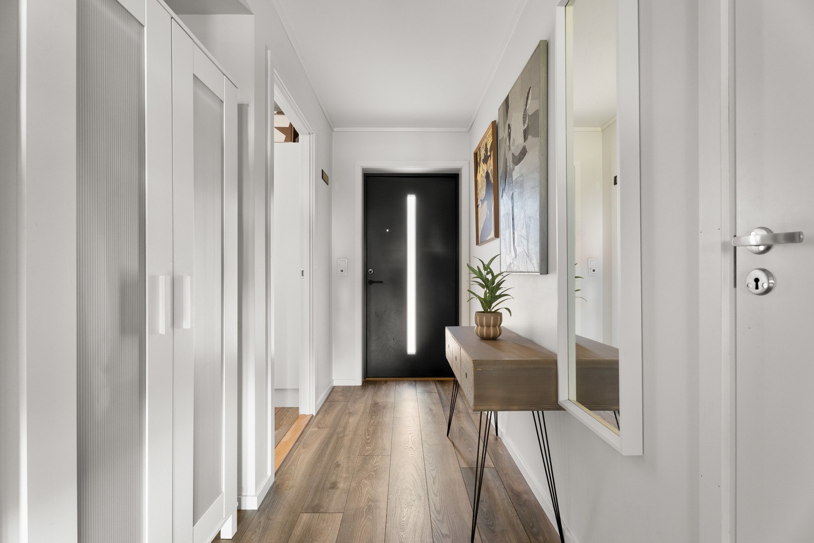 Vel inne blir vi ønsket velkommen i en fin entré med hvitmalte vegger og tidsmessig laminat på gulv med gulvvarme. Galleribilde