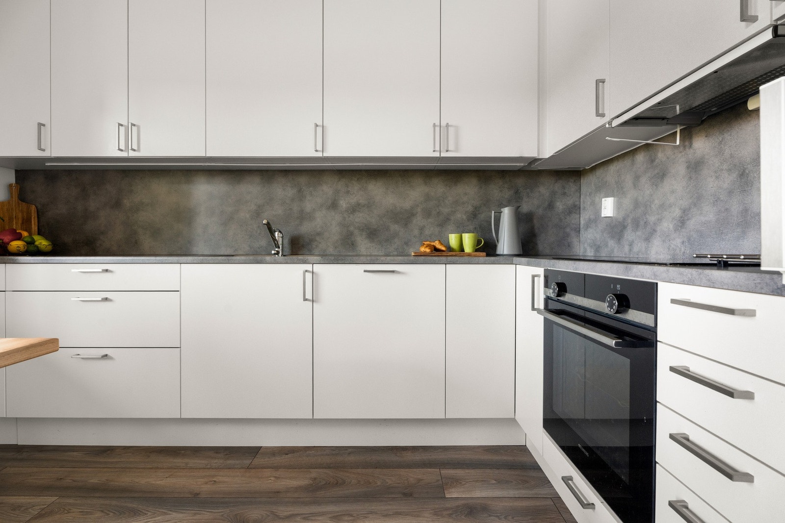 nnredningen har hvite, glatte fronter, takoppforede skap og grå laminatbenkeplate med planlimt kum i stål. Galleribilde