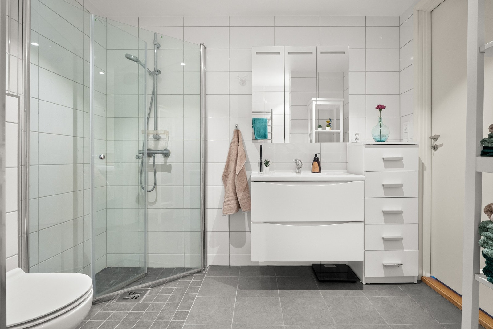 Badet har et vegghengt toalett, opplegg for vaskemaskin og et dusjhjørne med innfellbare glassdører. Galleribilde