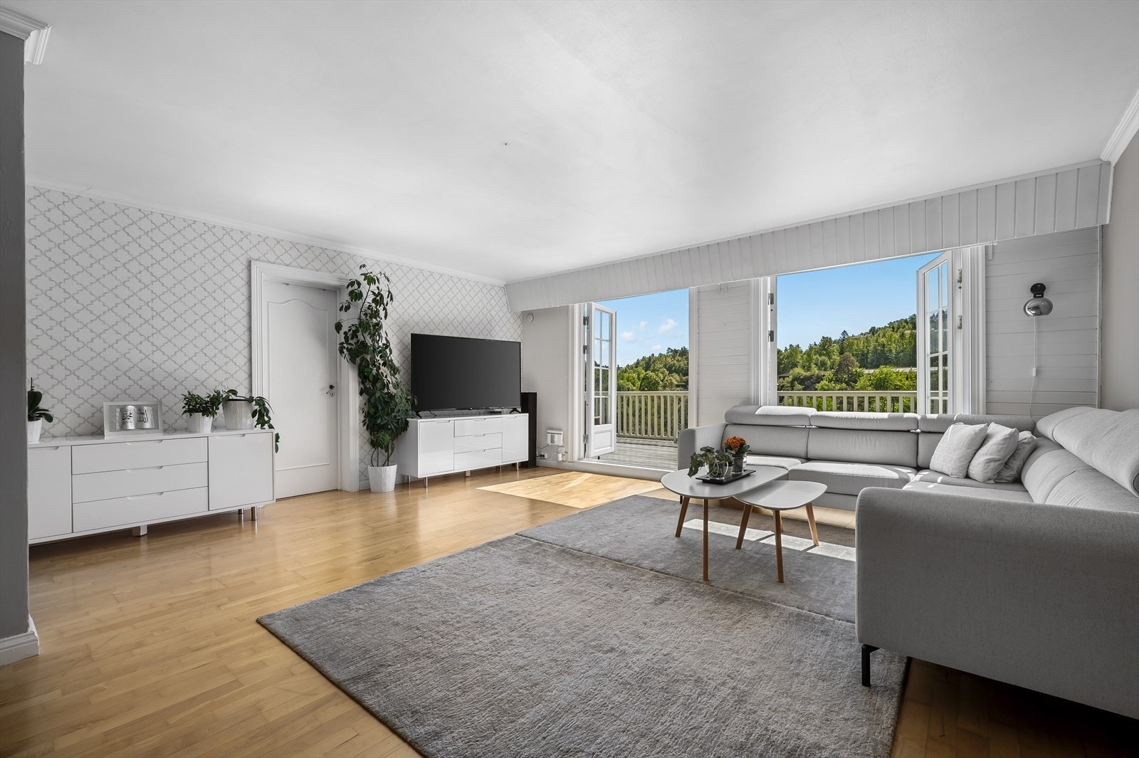 Stuen er romslig og luftig, og har to store dobbeltdører som åpner opp mot en sørvendt veranda. Galleribilde