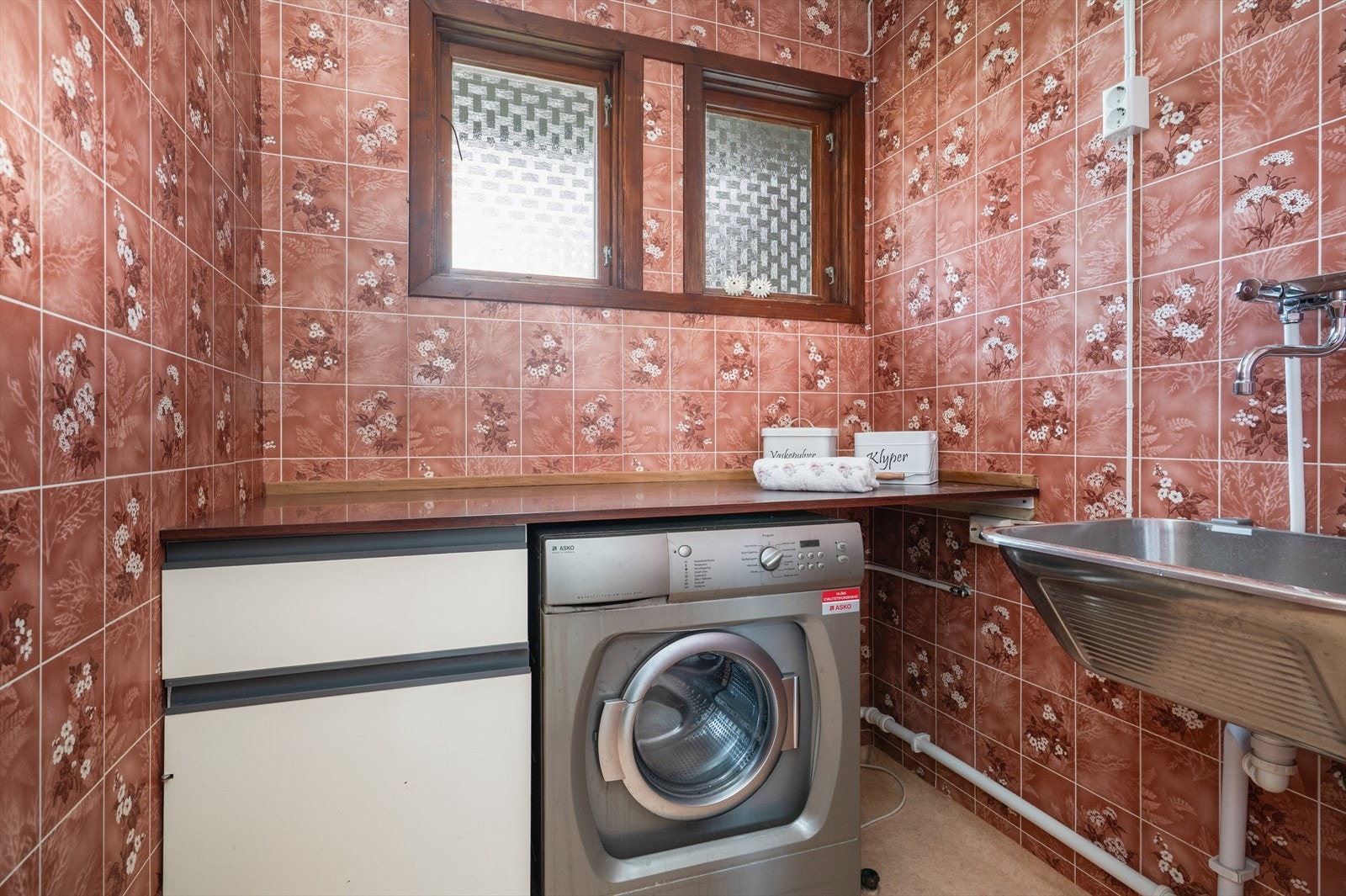 I hovedetasjen er det også et praktisk vaskerom fra ca. 1990 i følge selger. Her er det belegg på gulv og våtromstapet på vegger. Rommet har utslagsvask på vegg, plassbygget benkeplate med opplegg for vaskemaskin under. Galleribilde