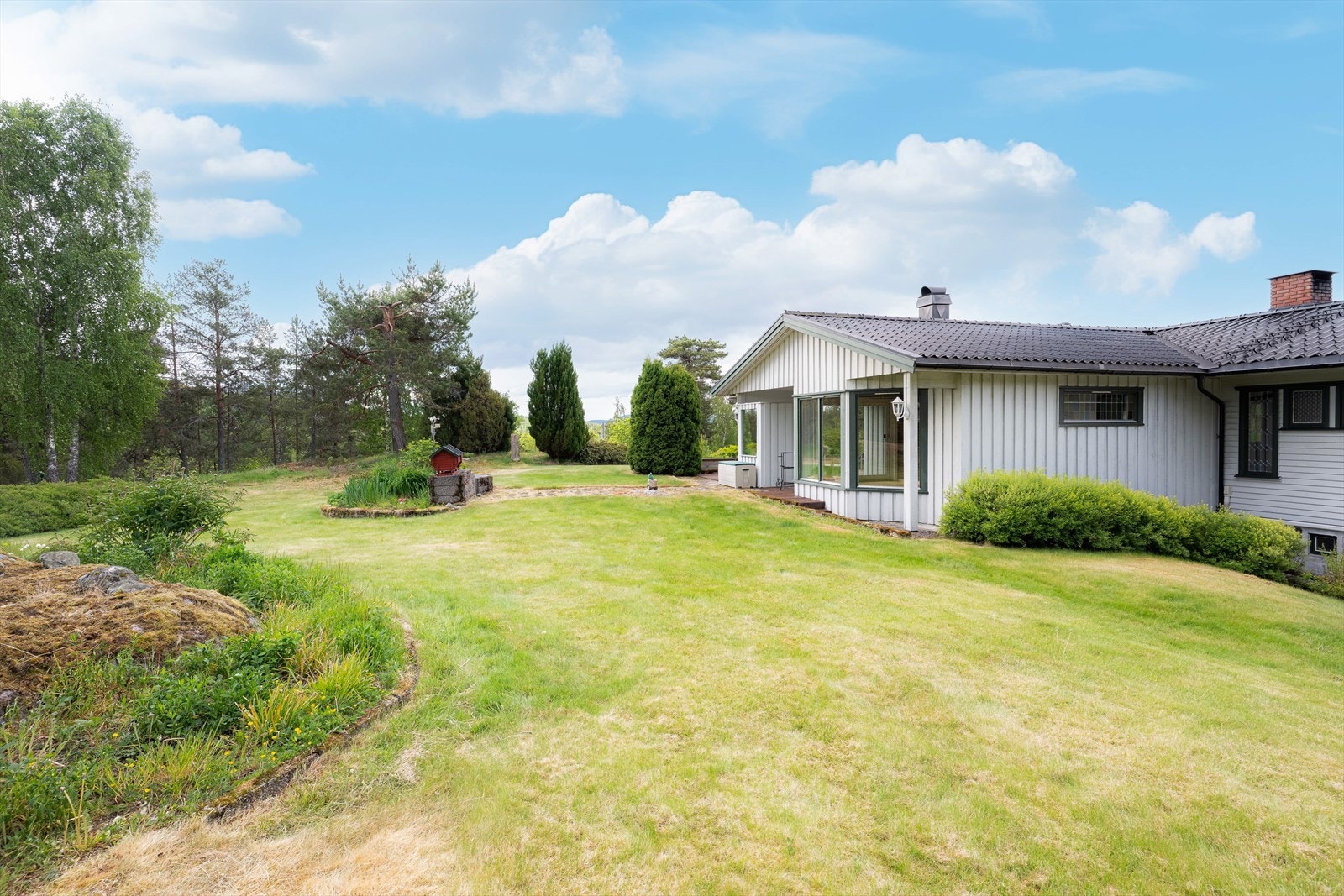 Hagen på østsiden av boligen har relativt plane arealer som gir god plass for lek og aktivitet. Her er det også nydelig beplantning av prydbusker og trær. Galleribilde