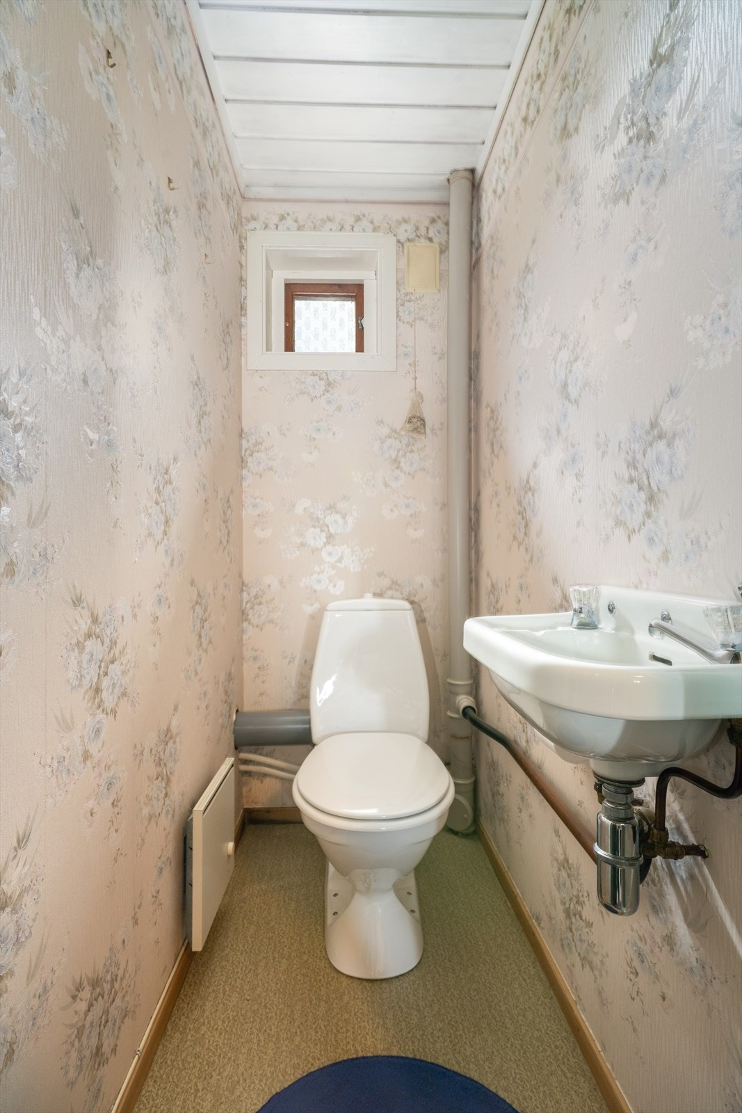 Eget toalettrom ligger praktisk til ved hallen i underetasjen. Rommet har en eldre standard med belegg på gulv, tapet på vegger og hvitmalt panel i himling. Galleribilde