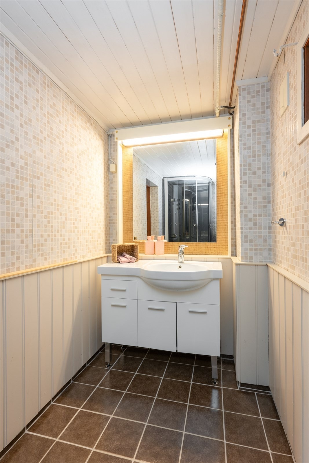 I kjeller er det også et eget, eldre baderom med flis på gulv, malt brystpanel i lys farge og tapet på vegger, hvitmalt panel i himling. Galleribilde