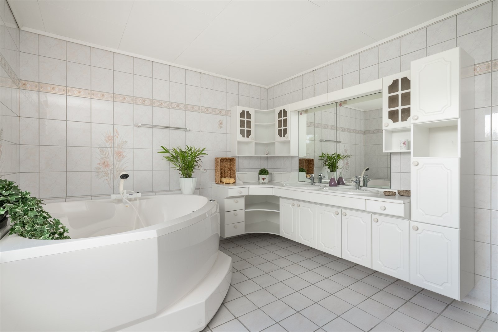 I hovedetasjen er det et stort, flislagt baderom av eldre standard. Her er det innredet med en romslig baderomsinnredning med flere skuffer og skap, benkeplate med to nedfelte servanter og to speilflater med belysning over. Galleribilde