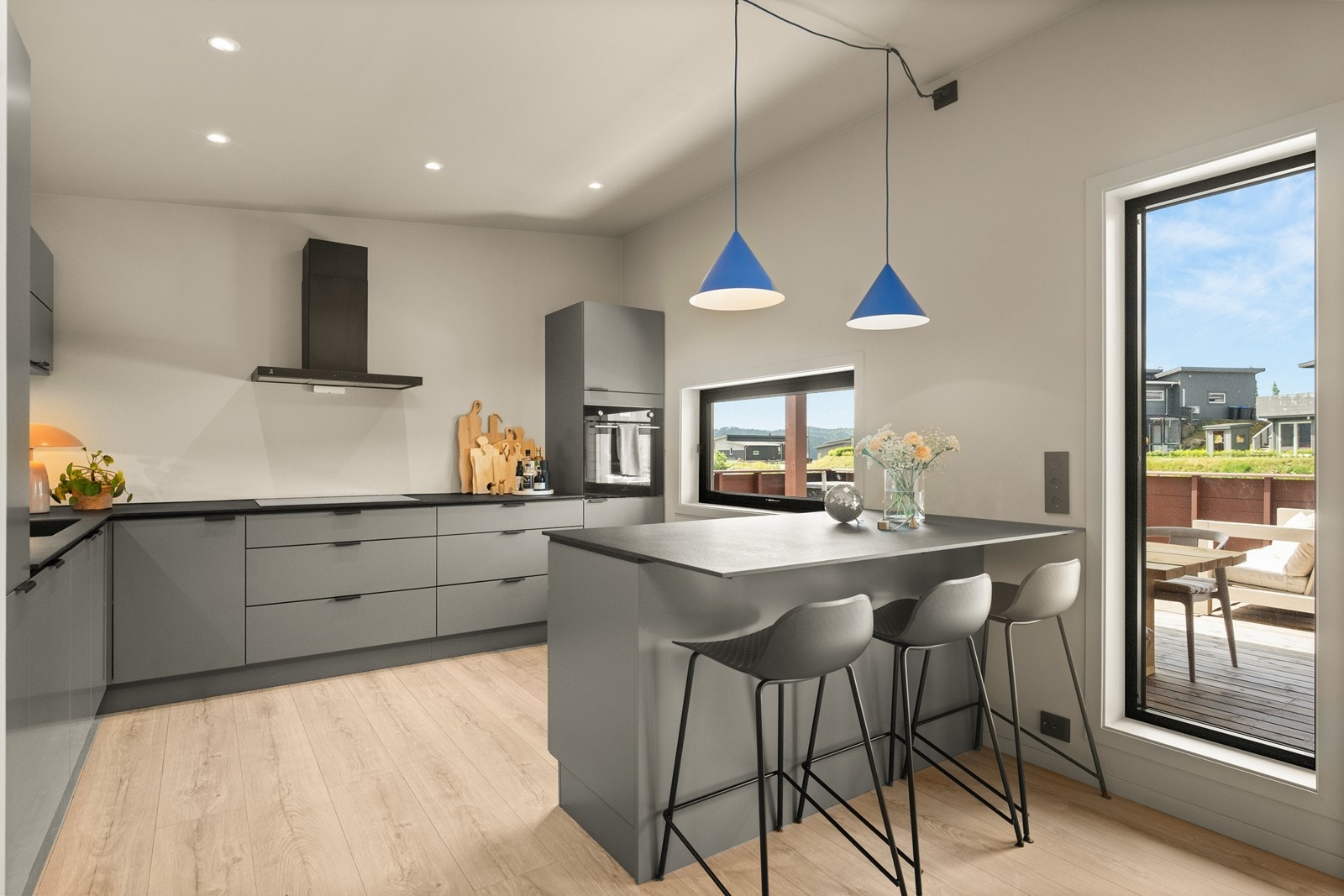 Kjøkken med ekstra takhøyde og spotter i taket. Sosial løsning med kjøkkenøy som har sitteplass. Galleribilde