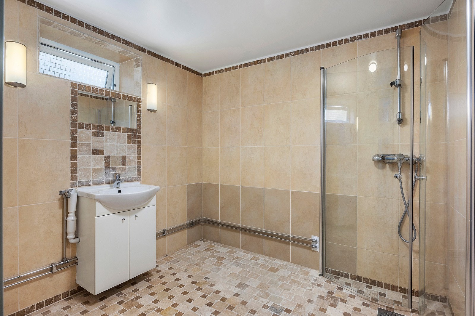 Flislagt bad med elektriske varmekabler og opplegg for vaskemaskin ved servant. Galleribilde