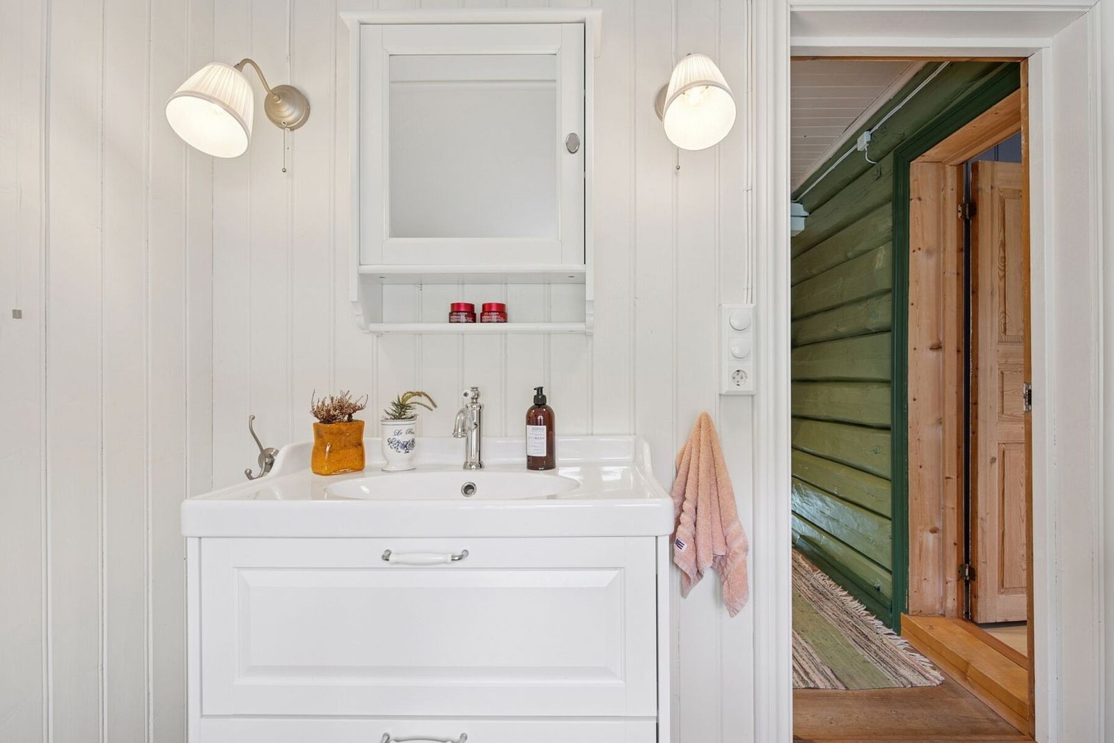 Praktisk toalettrom med heldekkende servant, flislagt marmorgulv og vegghengt skap med speil. Galleribilde