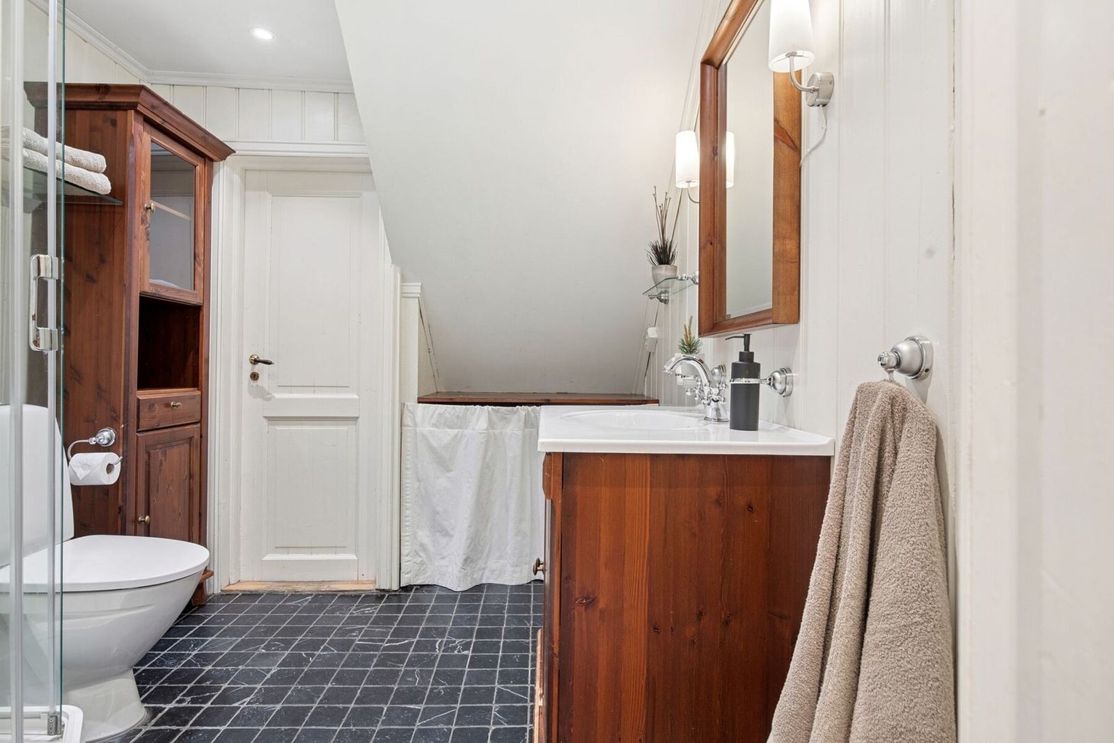 Badet er innredet med dusjkabinett, servantskap, opplegg for vaskemaskin og toalett. Galleribilde