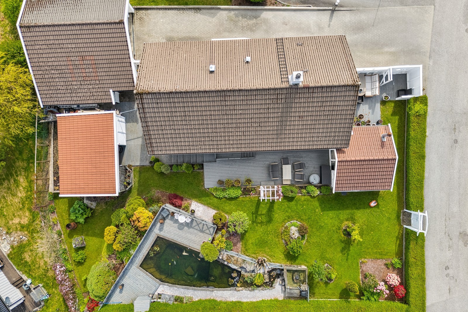 Fint opparbeidet hageanlegg med beleggningsstein i tilkomstveien og på parkering, store terrasser, plen og stor fiskedam. Galleribilde