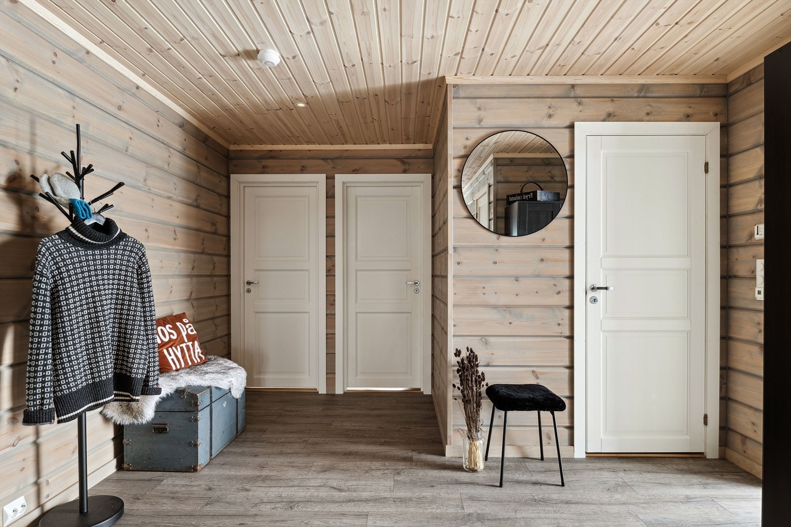 Når du entrer hytta kommer du inn i en lys og innbydende entré. God standard fra 2021 med enstavs laminat på gulv med gulvvarme, overflater med liggende panel og downlights i himlingen. Plass til sko og yttertøy i medfølgende garderobeskap. Galleribilde