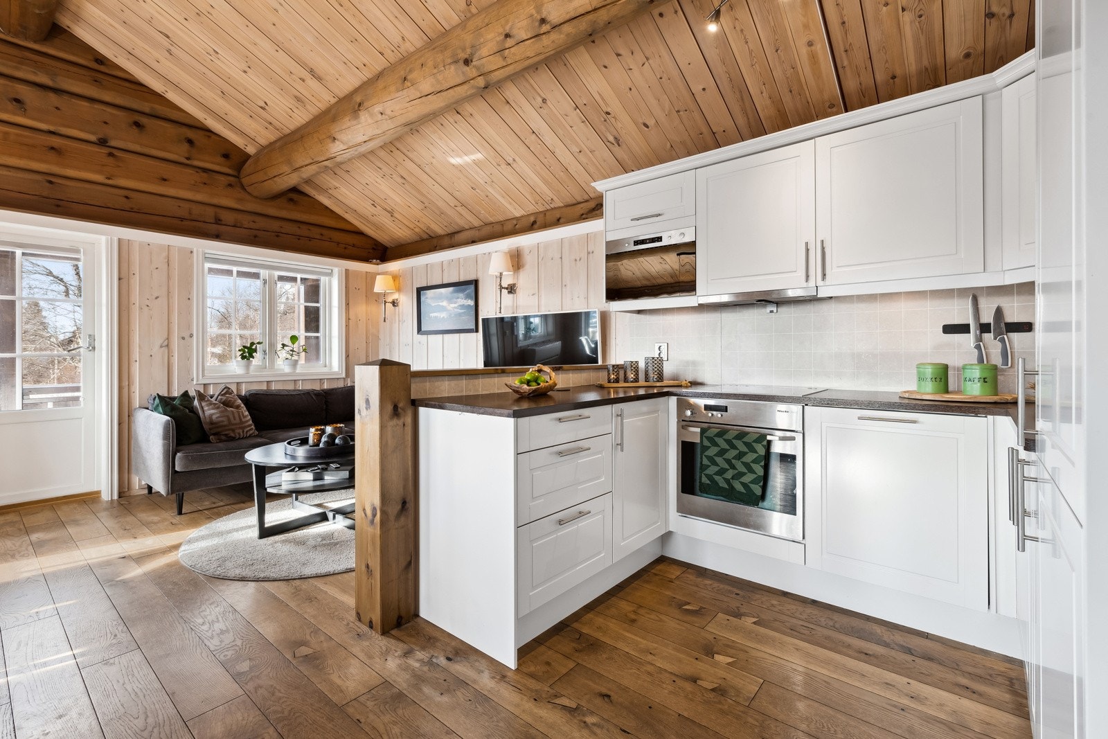 Åpen kjøkkenløsning med inredning fra byggeår. Innredningen har profilerte fronter. Galleribilde