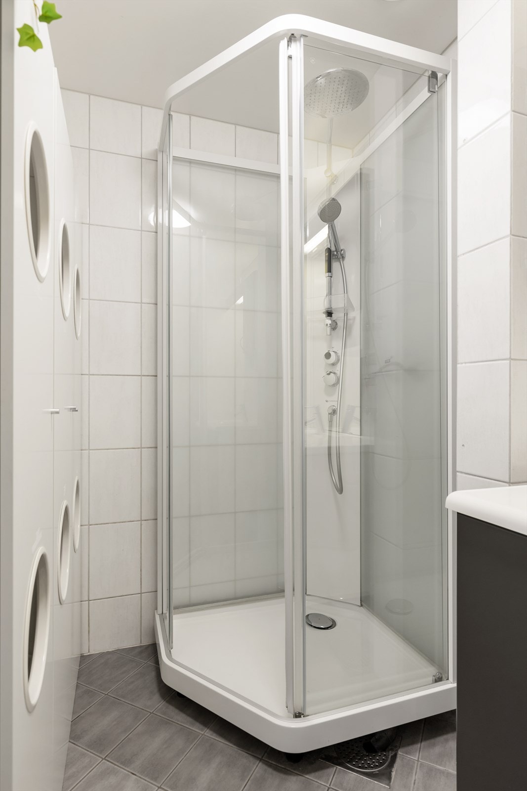 Badet er innredet med servant på innredning og dusjkabinett. Her er det også en praktisk og smart skittentøy-løsning. Galleribilde