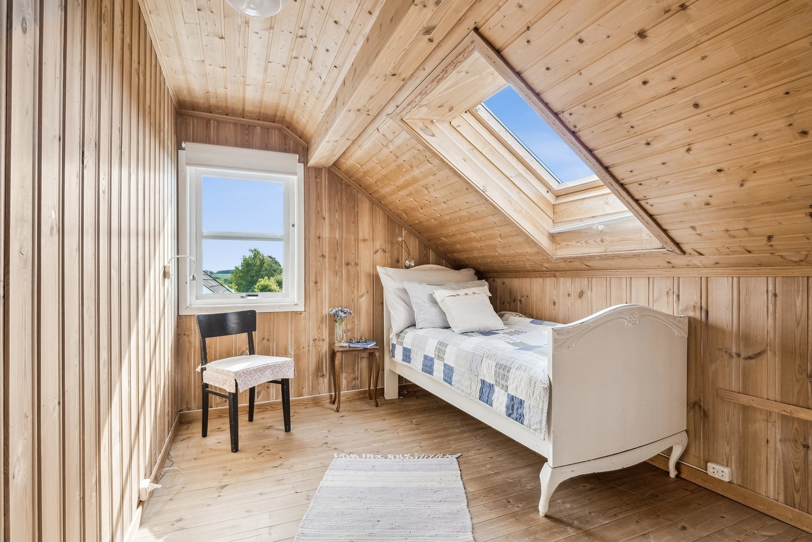 Koselig soverom med skråtak og takvindu. Panelte overflater og furugulv. Galleribilde