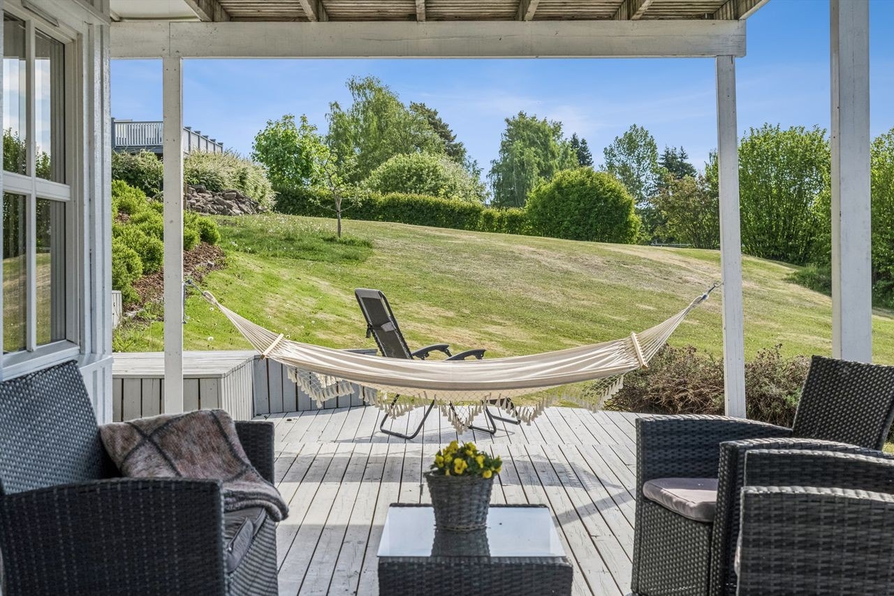 Fra terrassen på bakkeplan skuer man ut over den frodige og pent opparbeidede hagen! Galleribilde