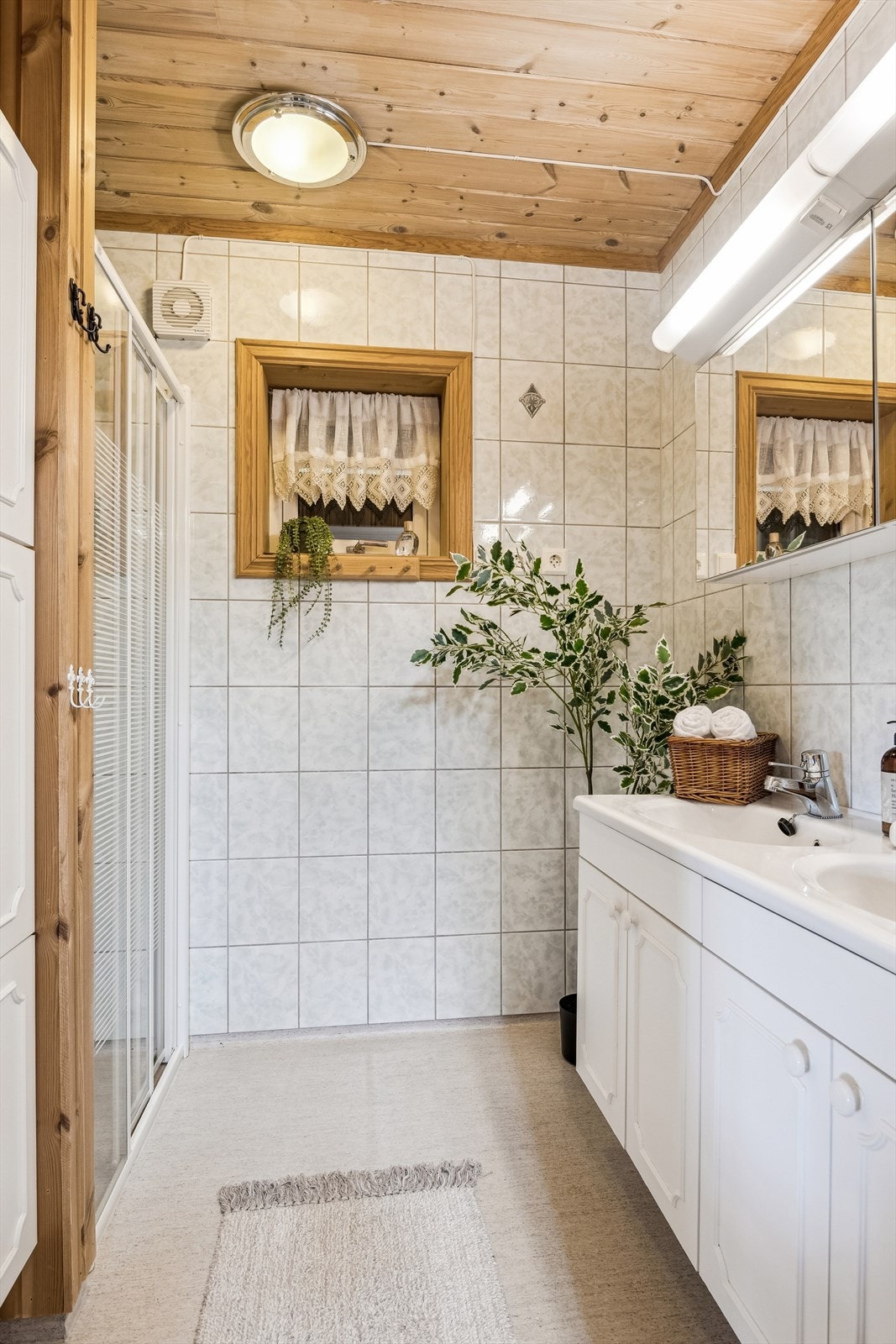 Bad i kjeller fra 1999, innredet med fliser på vegger og belegg på gulv. Dobbel servant. Dusjhjørne. Galleribilde