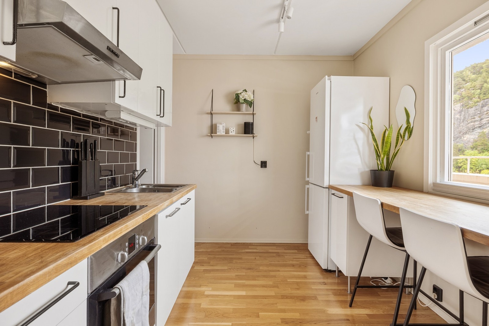 Stilrent og moderne kjøkken med slette fronter, benkeplate i tre og stålvask. Galleribilde