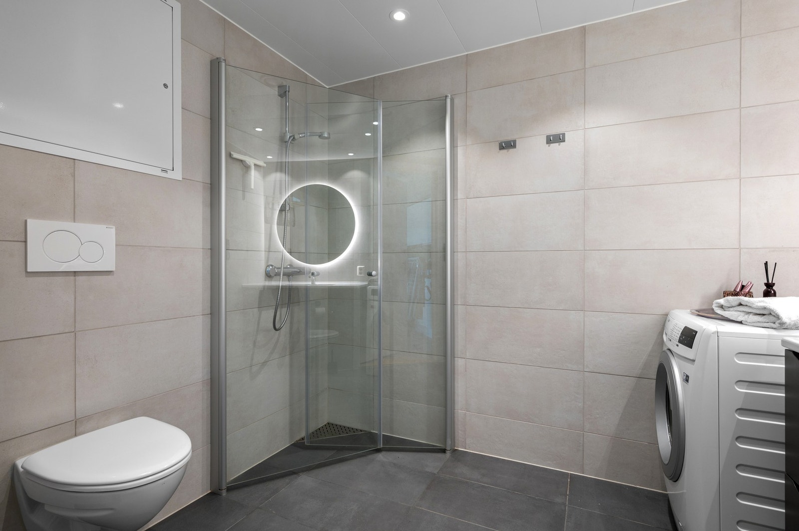 Utstyrt med veggmontert wc, rørfordelingsskap, servantskap, mekanisk avtrekk og innfellbare dusjdører. Galleribilde