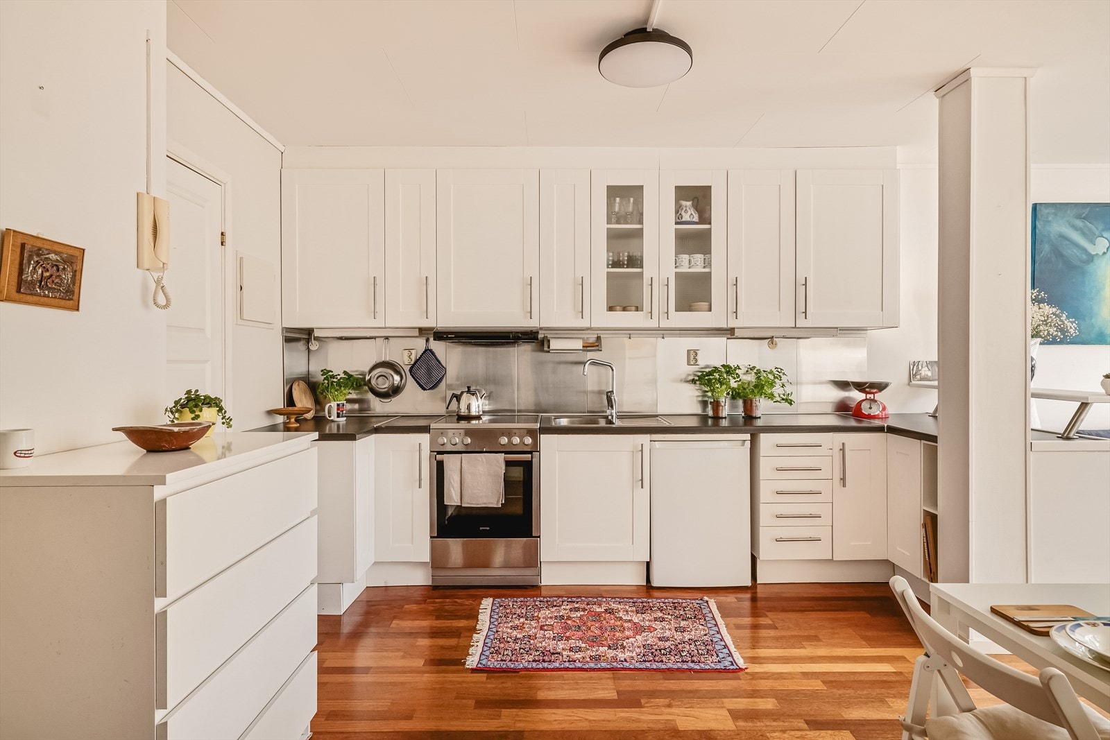 Kjøkken er tidløst i profilerte hvite fronter, og har takhøye overskap. Langstrakt benkeplate og god skapplass. Galleribilde