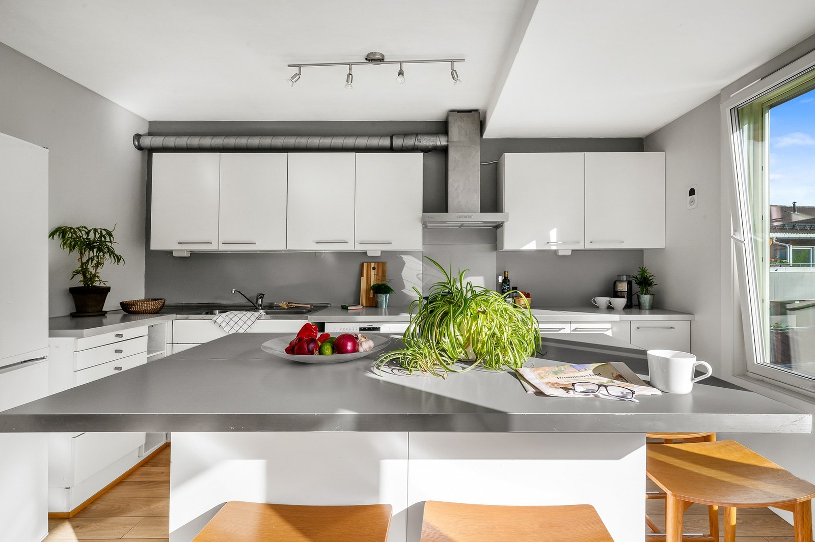 Kjøkkeninnredning med hvite slette fronter og benkeplate av laminat. Kjøkkenet er utstyrt med frittstående hvitevarer som kjøleskap, komfyr med platetopp og oppvaskmaskin. Galleribilde