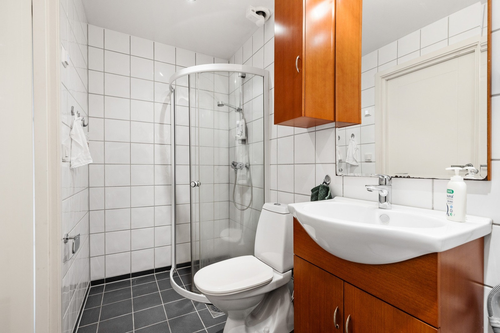 Rommet er innredet med servantinnredning, gulvstående toalett og dusjhjørne med skyvedør og veggmontert to-greps blandebatteri Galleribilde