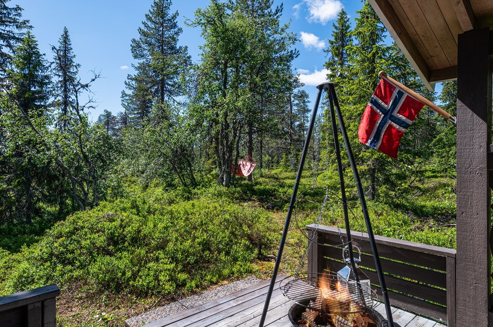 Tomtens plassering gir en skjermet og lun atmosfære. Det overbygde inngangspartiet med terrasse har plass for utemøbler, bålpanne og grill for kos og hygge i sola. Galleribilde