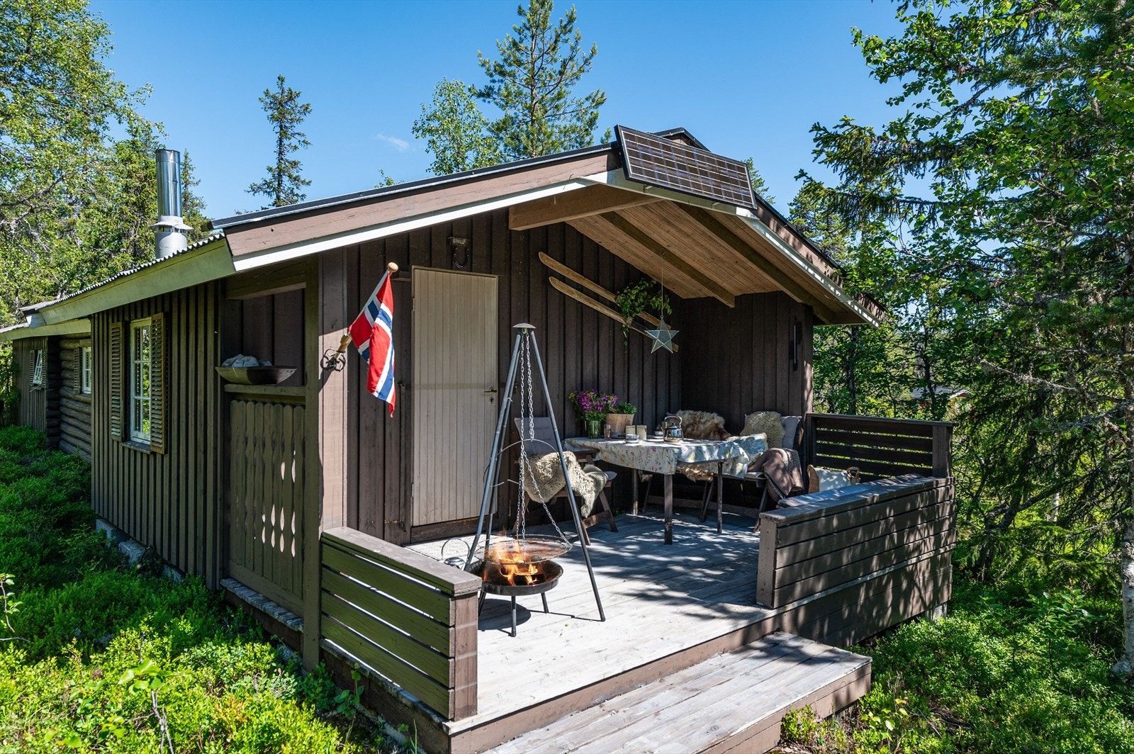 Sommeridyll. Hytta ligger lunt og fint til i terrenget og har en hyggelig adkomst via terrasse som er delvis overbygd. Her kan du nyte solen hele dagen. Galleribilde