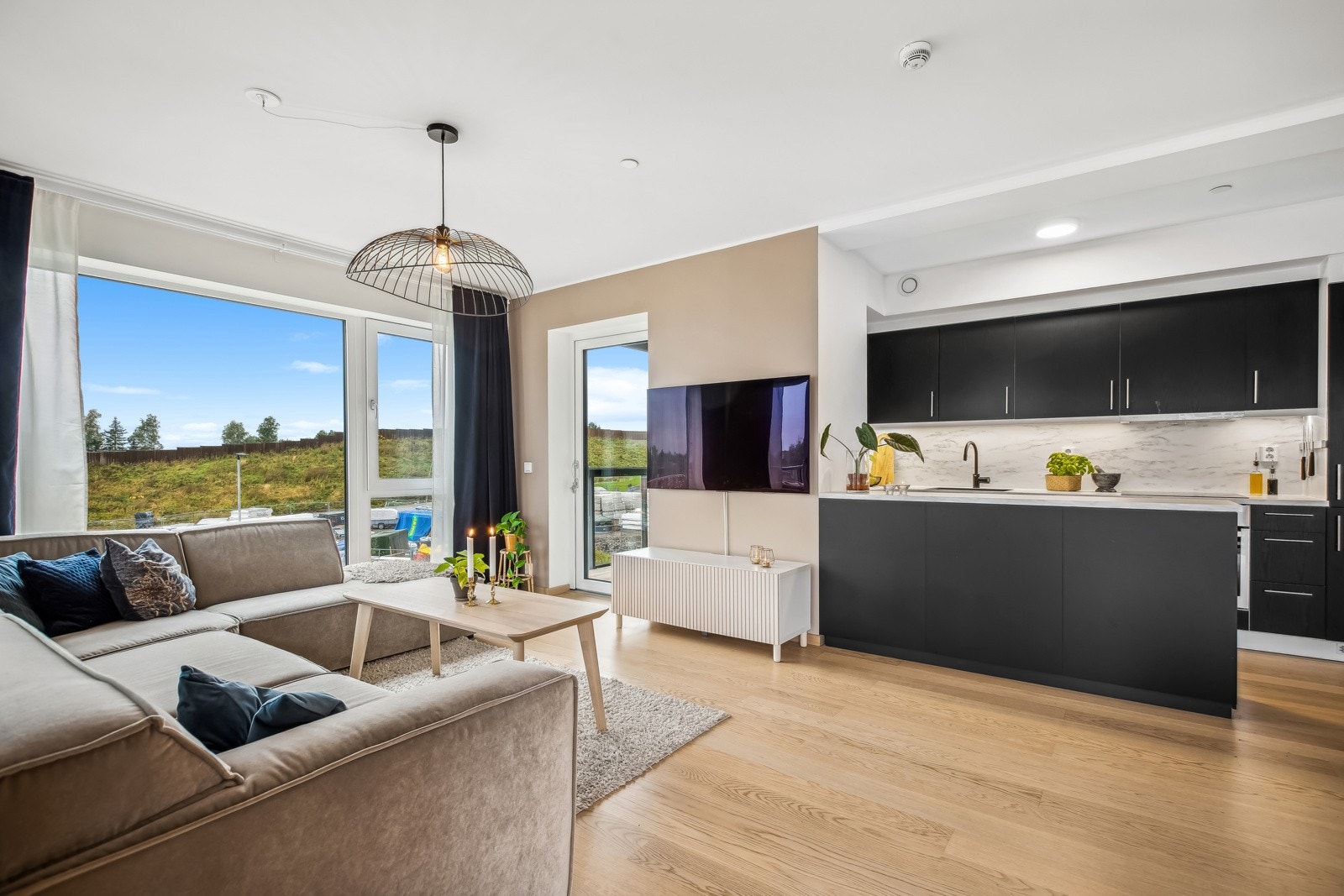 Kjøkkenet er i moderne stil med sorte skap og en herlig benkeplate i laminat. Galleribilde