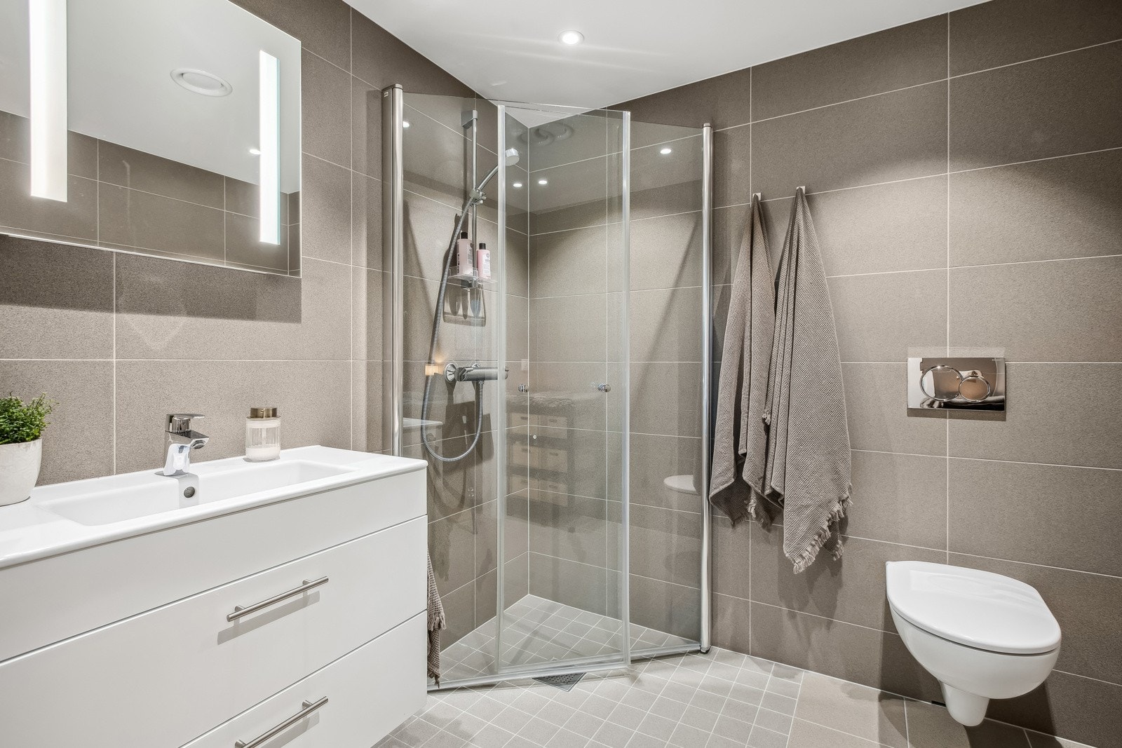 Baderommet er utstyrt med vegghengt servant og hjørnedusj. Galleribilde