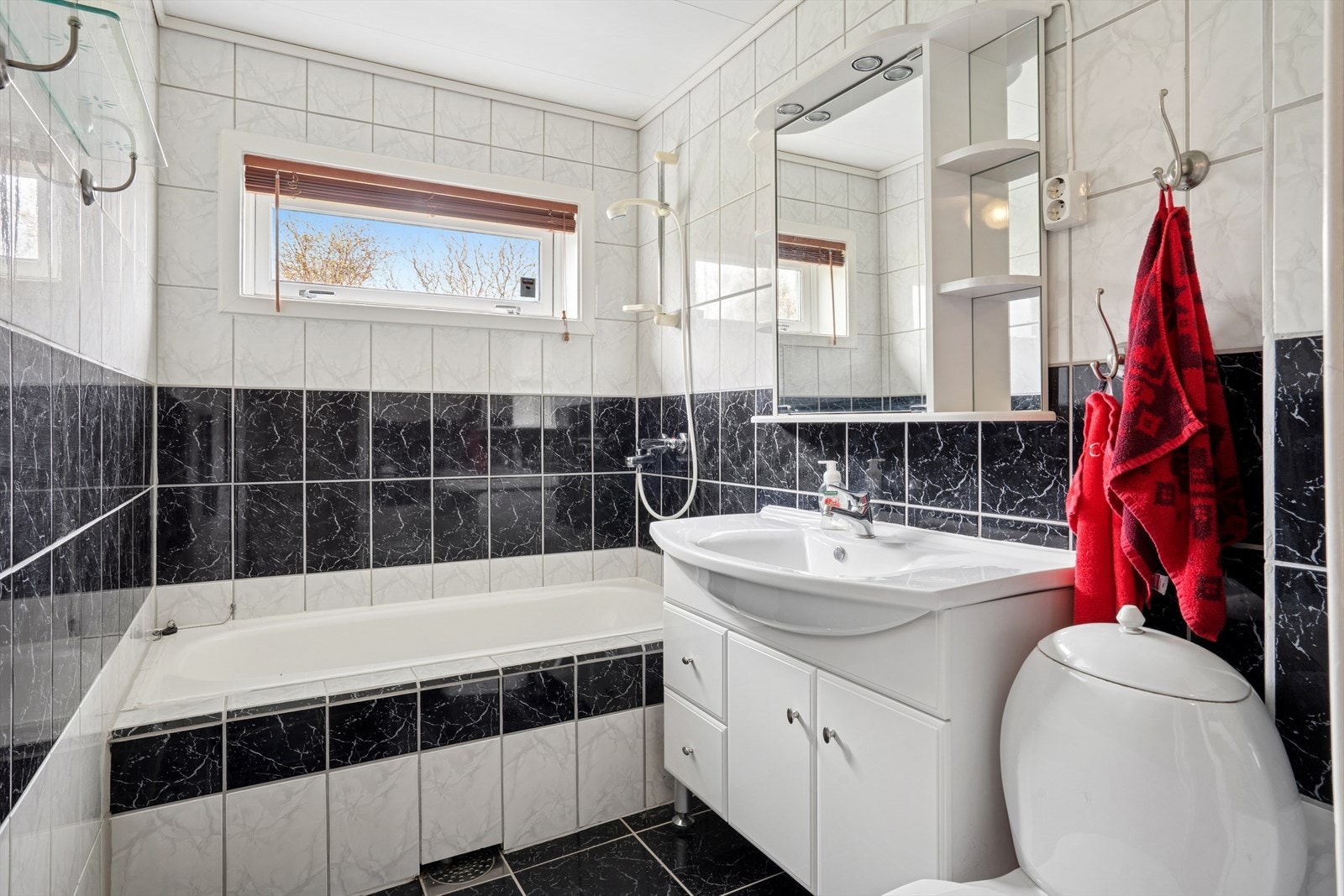 Flislagt bad i kjeller med servant med underskap, speil, dusj og toalett. Galleribilde