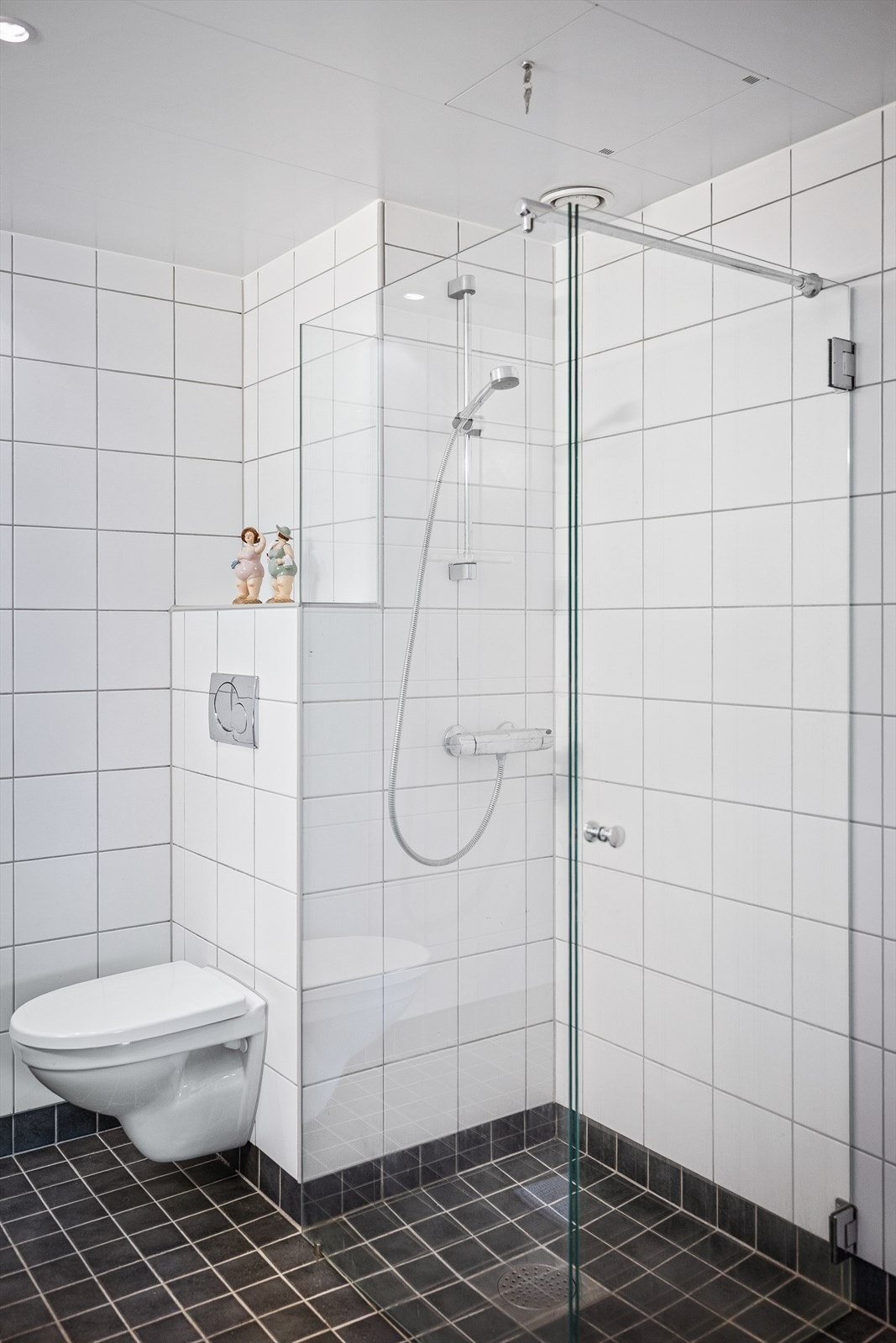 Videre har badet vegghengt toalett med innebygd sisterne, og dusjsonen er avskjermet med en fastmontert vegg og en innfellbar glassdør i herdet glass - en løsning som gir god romfølelse. Galleribilde