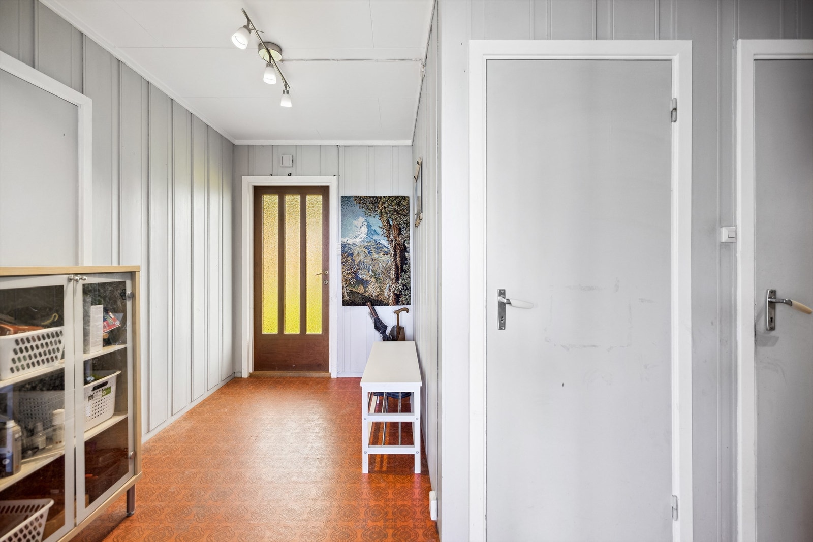 Her kommer du inn i en romslig entré med mønstrete belegg på gulvet og lysmalte vegger. Entréen er smal og går over i en gang med adkomst til alle rommene i boligen. Galleribilde